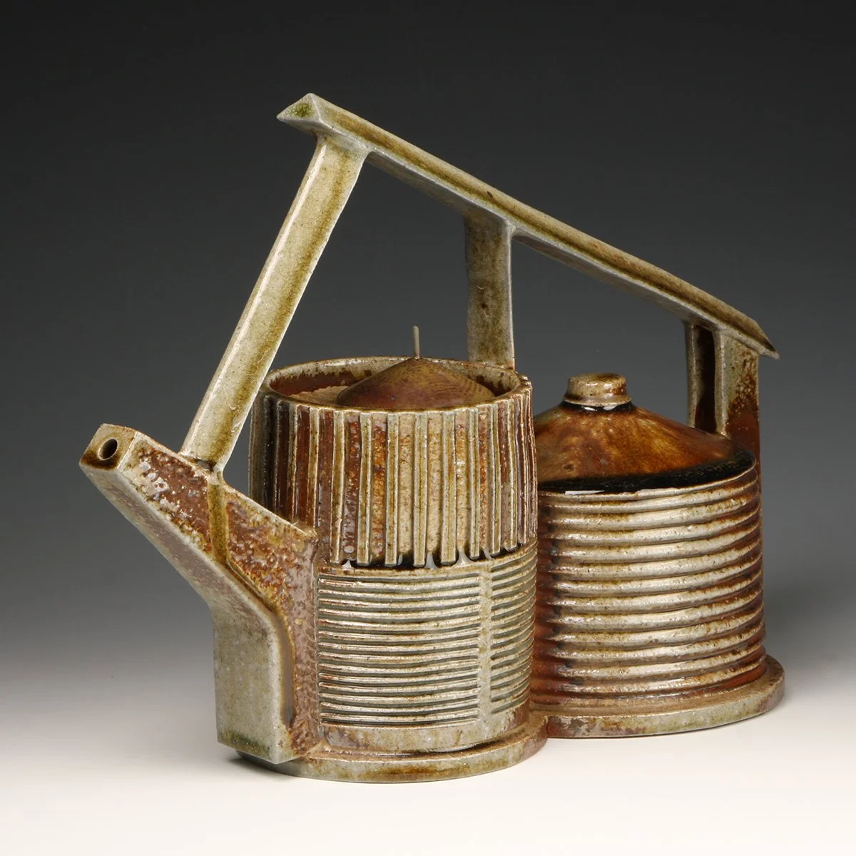 Rusty ceramic sculpture of two cans with a handle on top, resembling a toy or artistic piece.