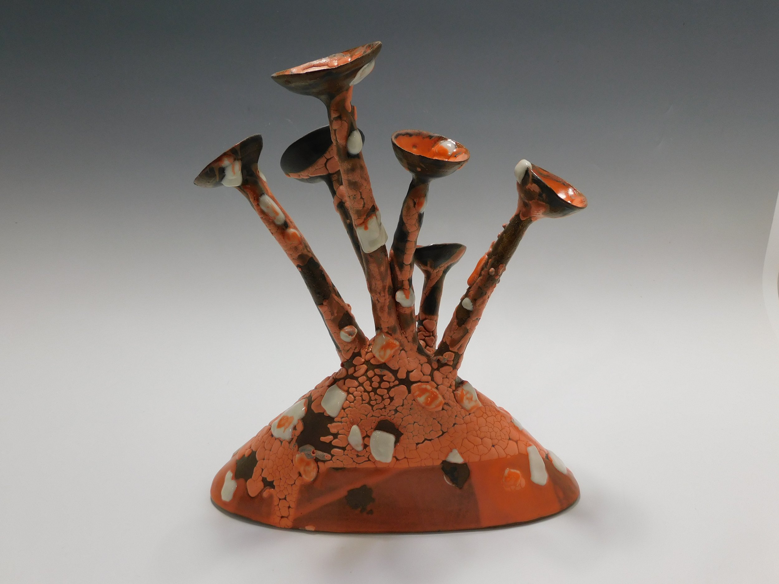 Ceramic sculpture of abstract mushrooms with orange, black, and white colors.