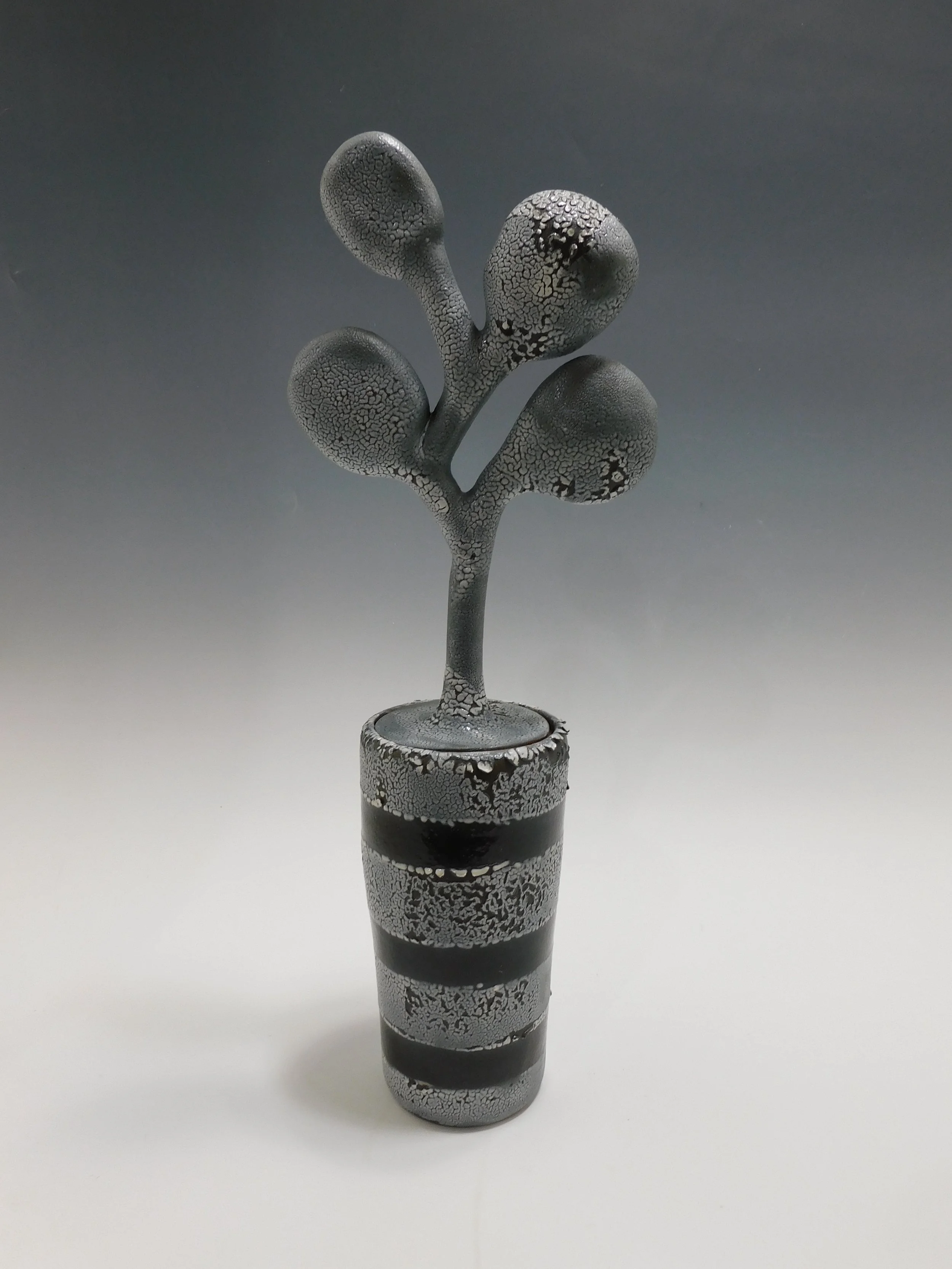 A black and gray marbled ceramic plant sculpture resembling a plant with three rounded buds in a striped vase.
