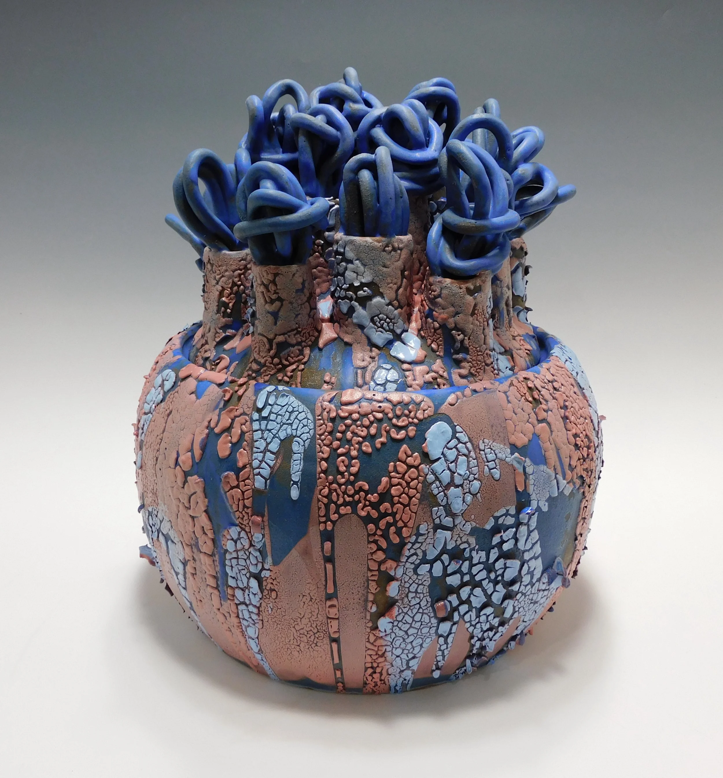 Ceramic vase with textured surface and blue and pink glazes, topped with numerous blue curly ceramic loops