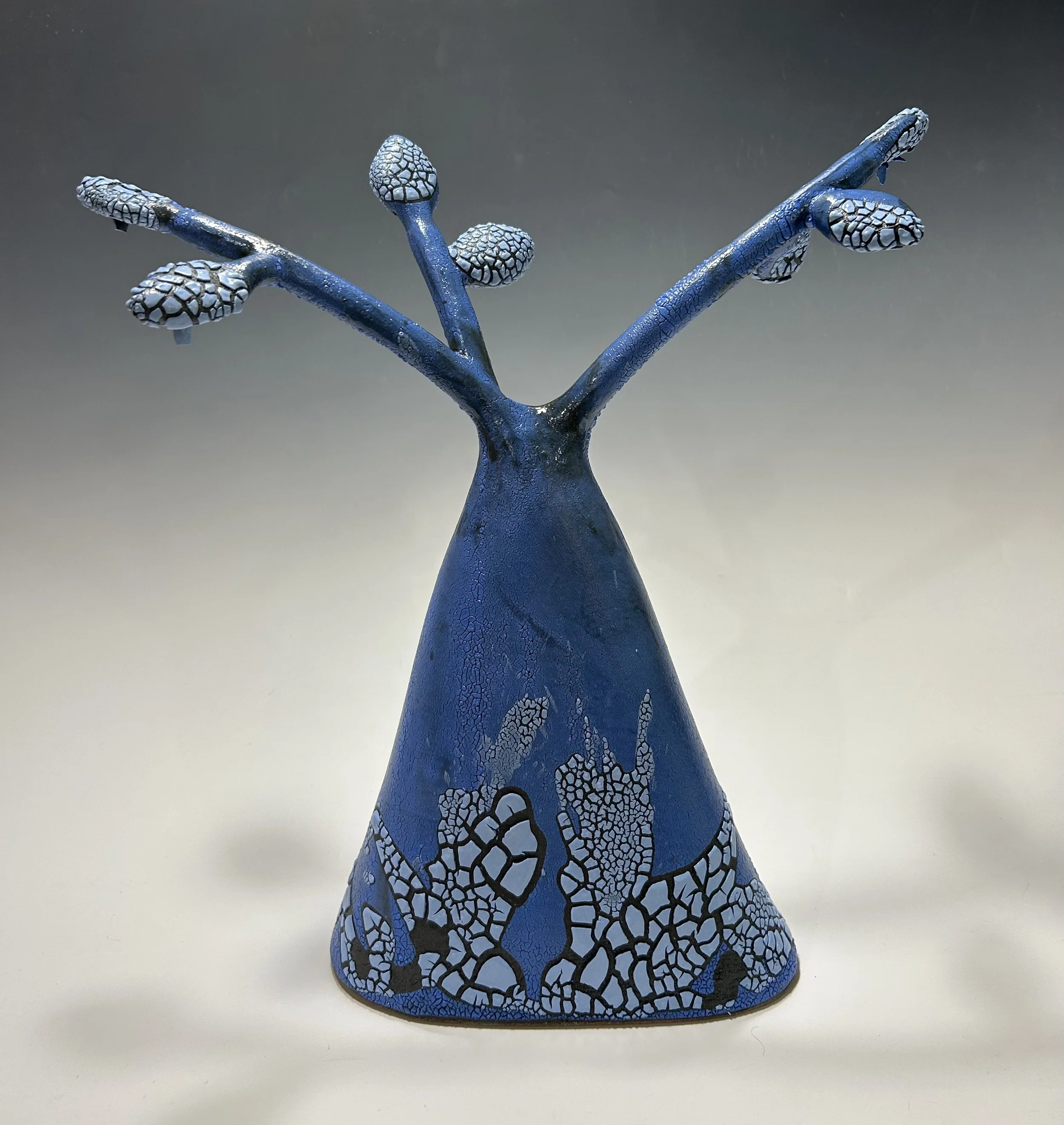 Blue ceramic sculpture resembling a tree with branching limbs and a cracked pattern on the surface.
