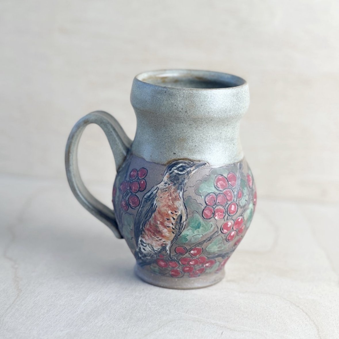 Handcrafted ceramic mug with bird and berry design