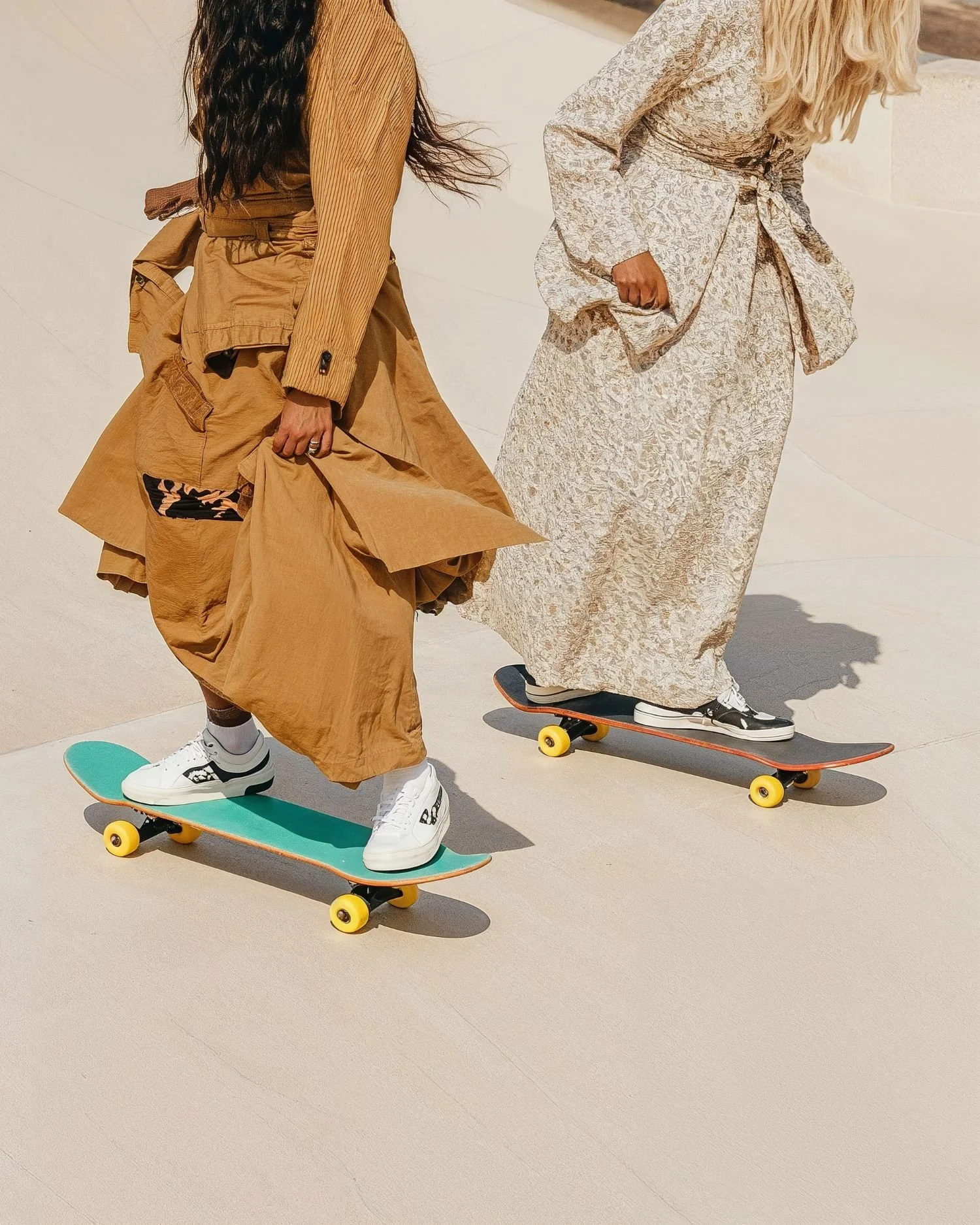 Zwei Personen in langen Kleidern auf Skateboards