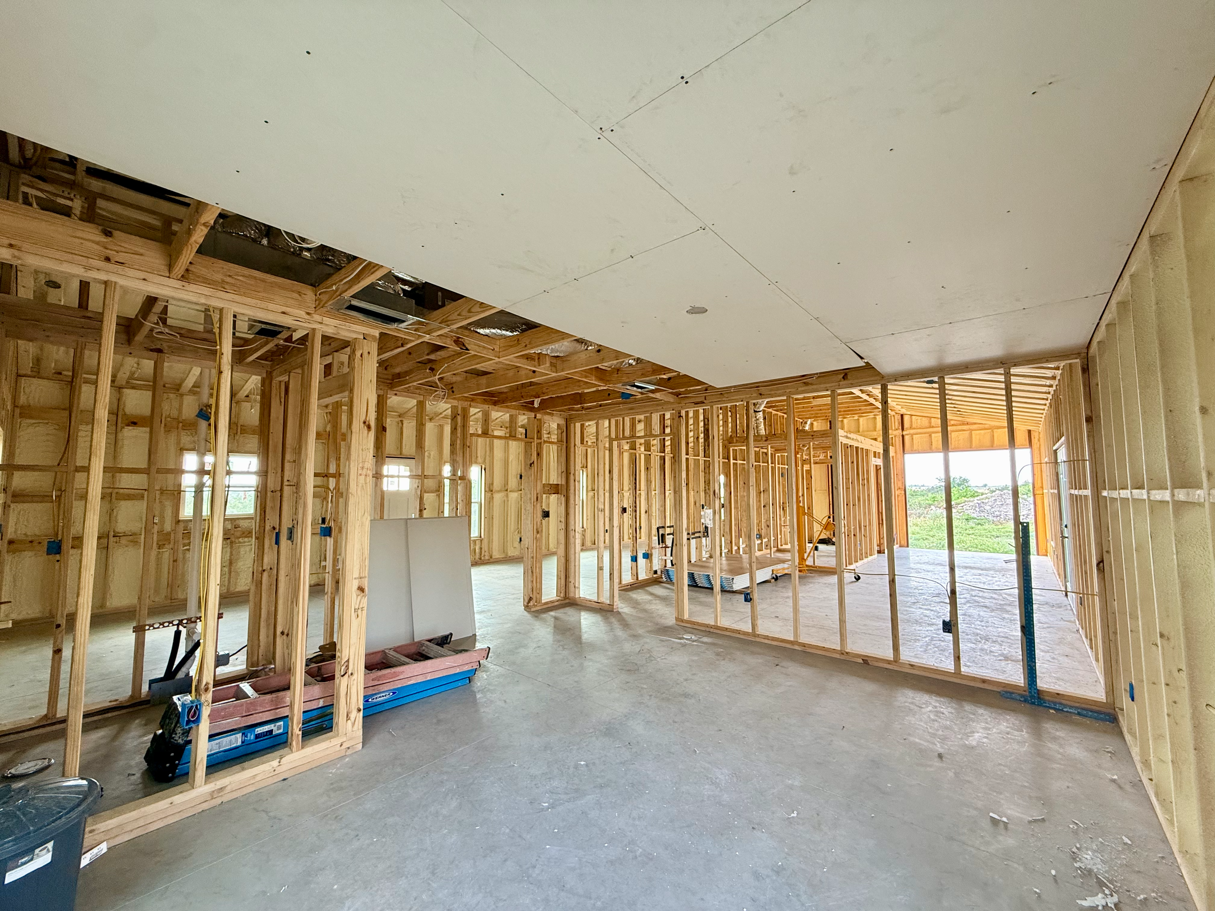 Construction site of a house interior with wooden framing and drywall installation on the ceiling.