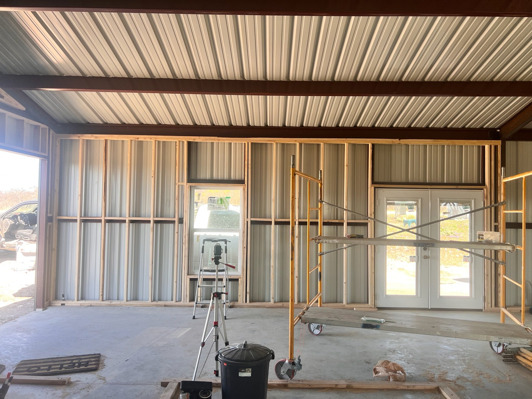 Interior of a building under construction with metal framing, scaffolding, and construction tools.