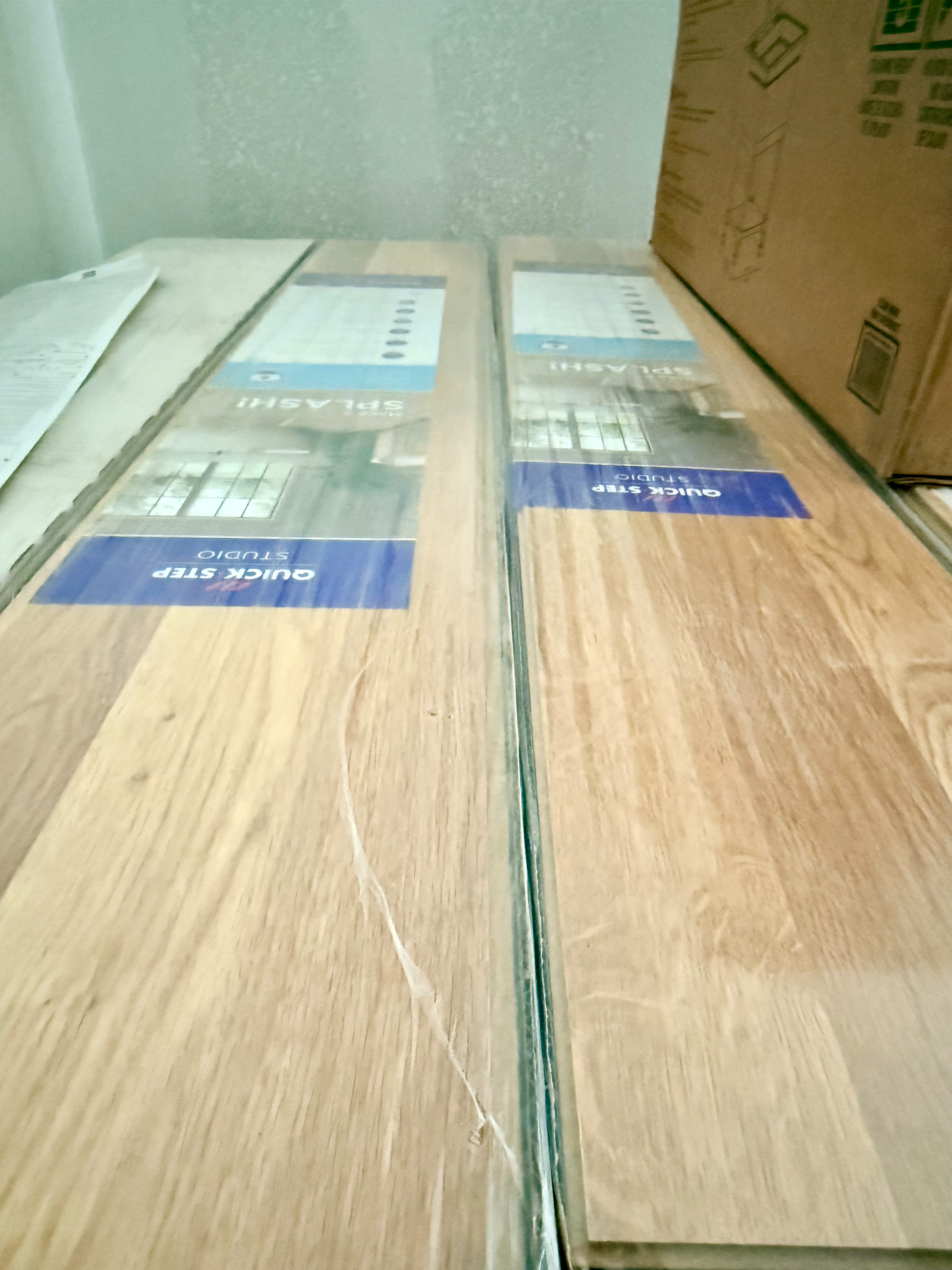The image shows a close-up view through a glass surface with the reflection of a wooden desk with boxes and paper documents on it.