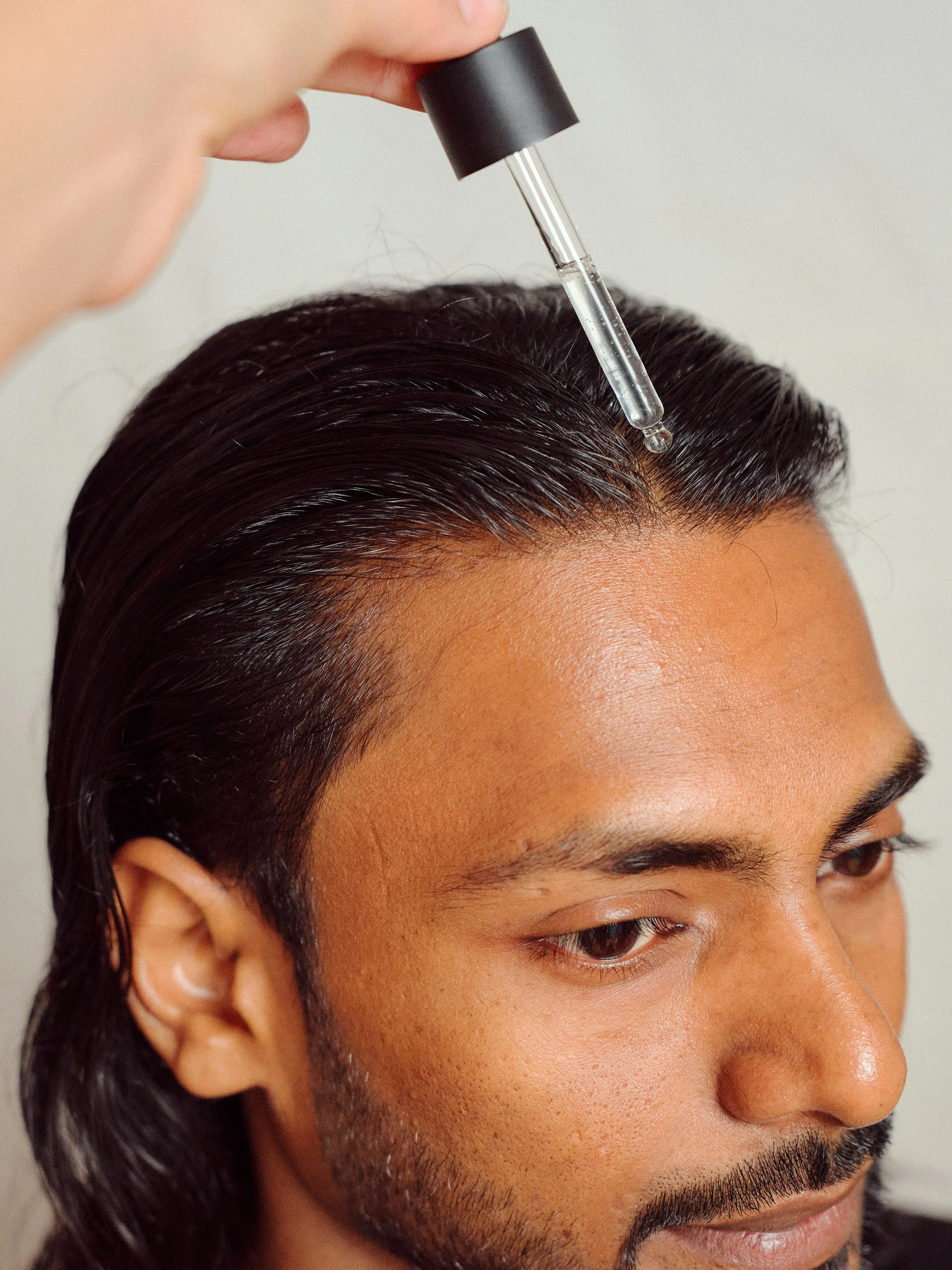 a man applying rosemary oil to his scalp