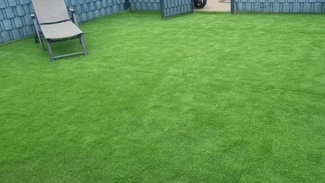 Dachterrasse mit grünem Kunstrasen und einem Liegestuhl.