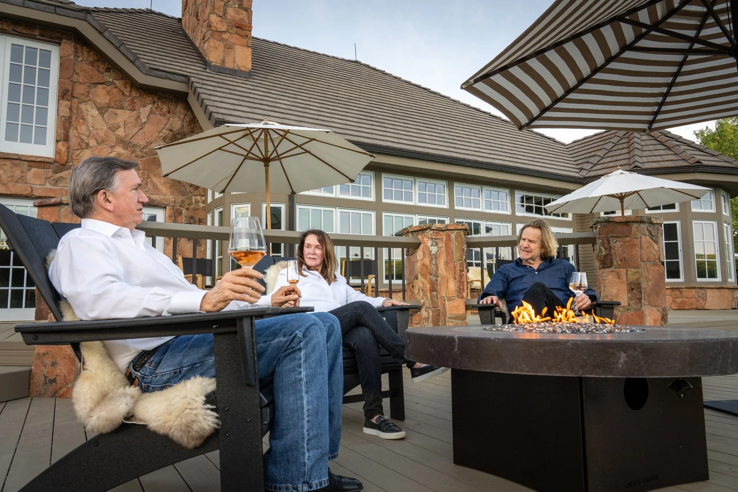 Guests around the fire pit at Rivenrock Lodge with wine