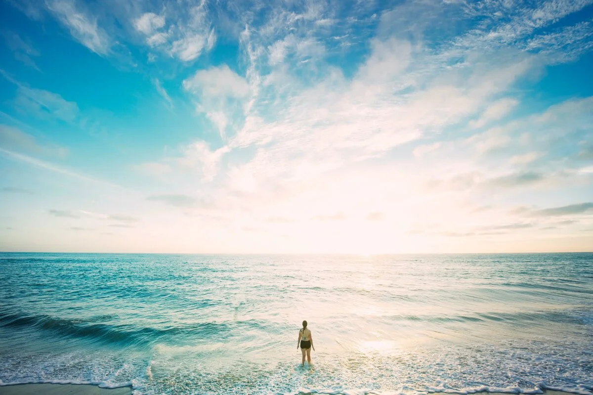 Woman on sea in front of sun