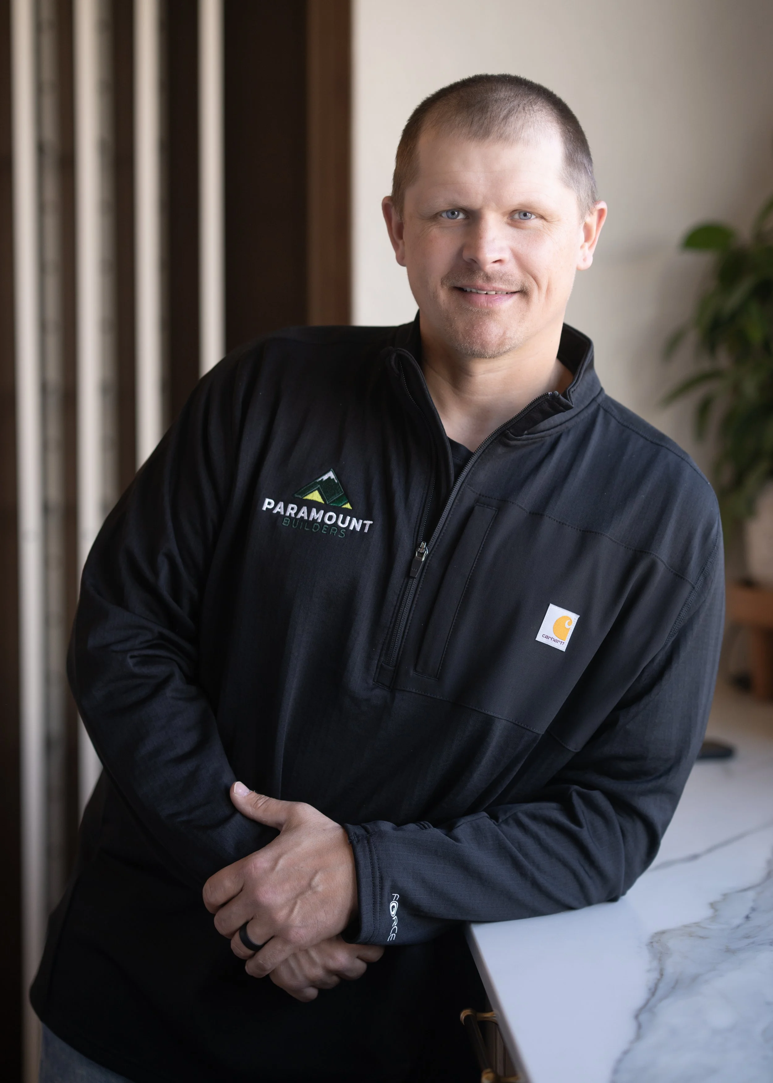 A person wearing a black Paradigm Solar Power, Inc. polo shirt, smiling, with a neutral gray background.