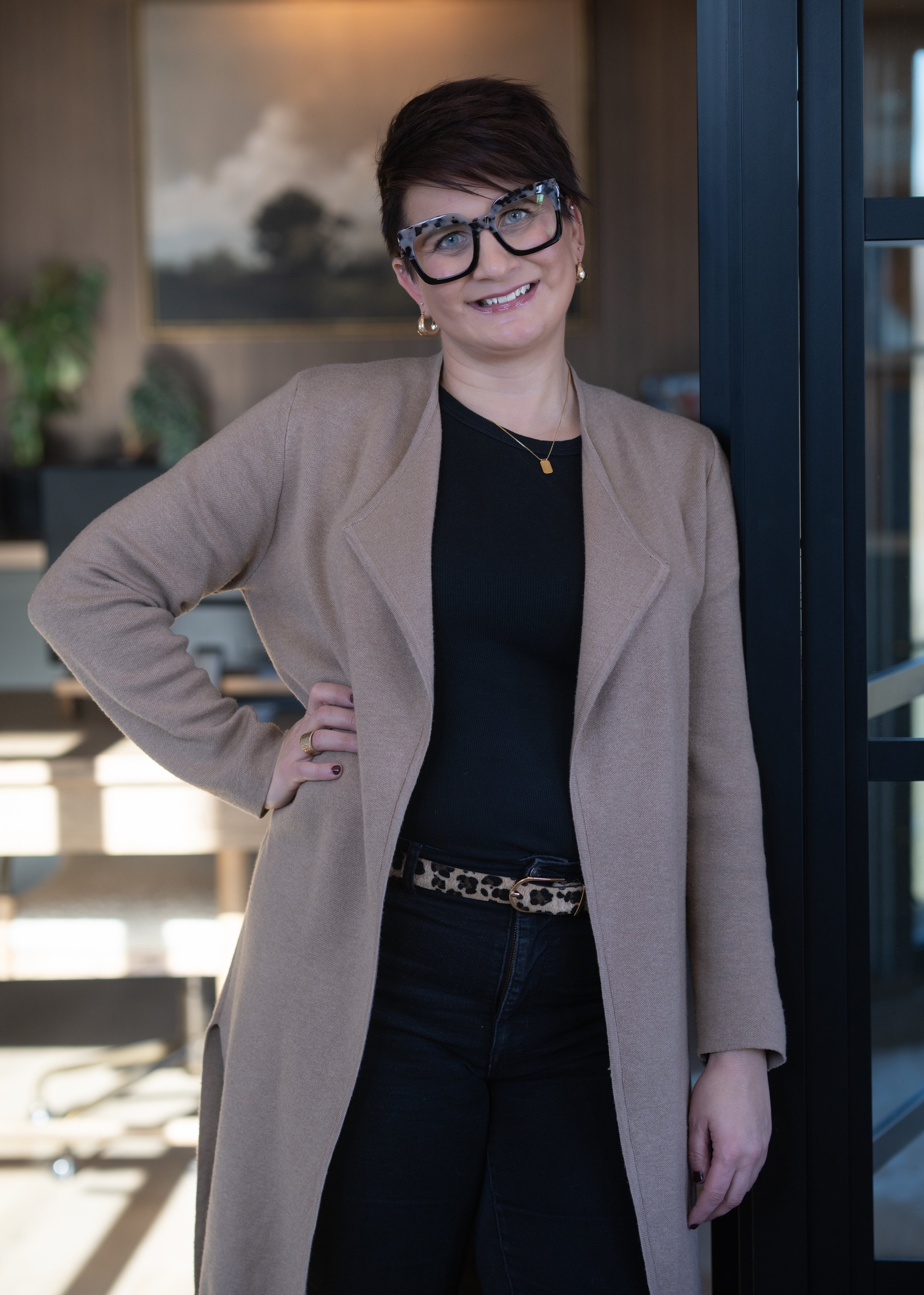 Person wearing a dark blazer and white blouse against a gray background.