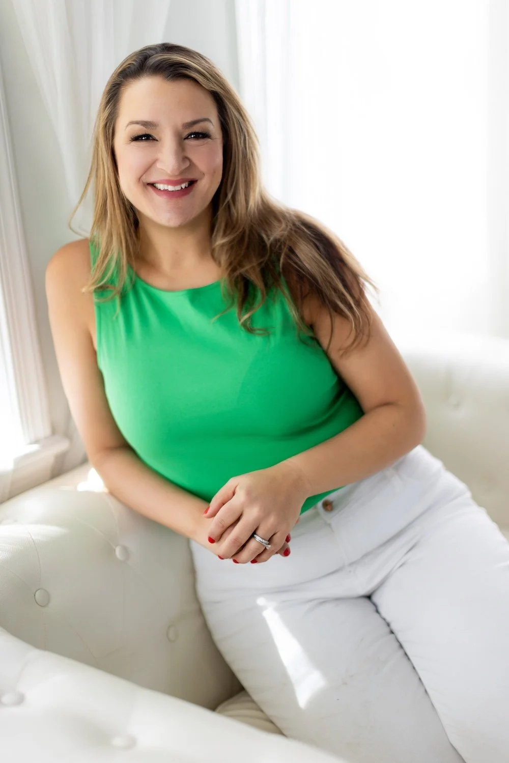 Caryn Grafton sitting and smiling, reclining on a white couch