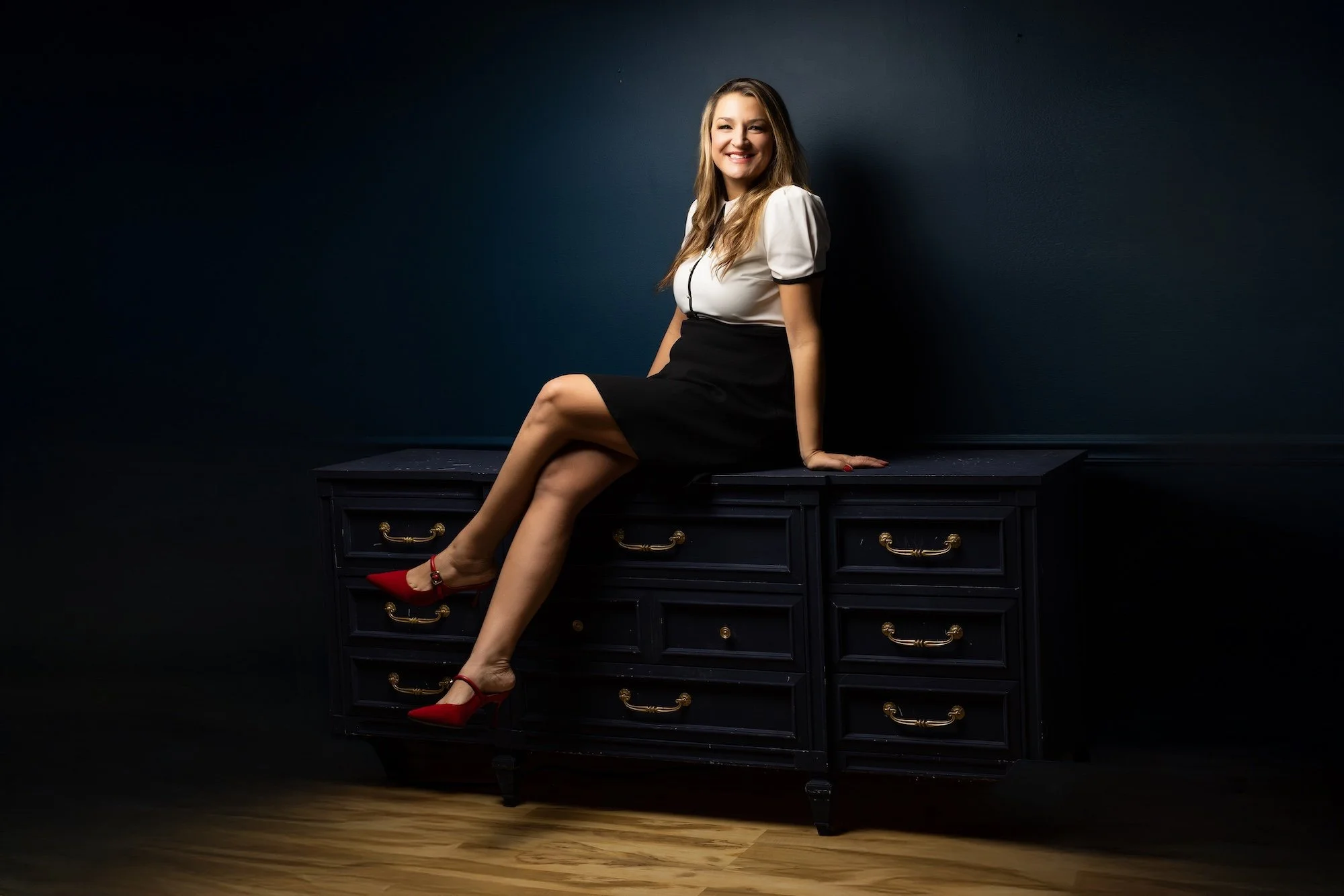 Caryn Grafton, professional studio headshot, sitting and smiling on a sidebar