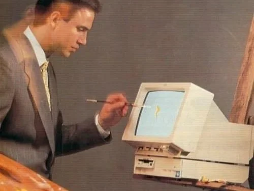 A man in a suit painting on a computer monitor with a paintbrush.