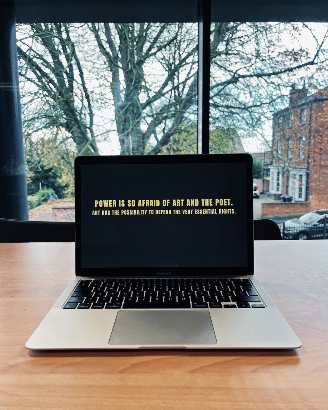 A laptop on a table displaying a quote: 'Power is so afraid of art and the poet. Art has the possibility to defend the very essential rights' a quote from poet Ai Weiwei. Displayed as part of a manifesto writing workshop.
