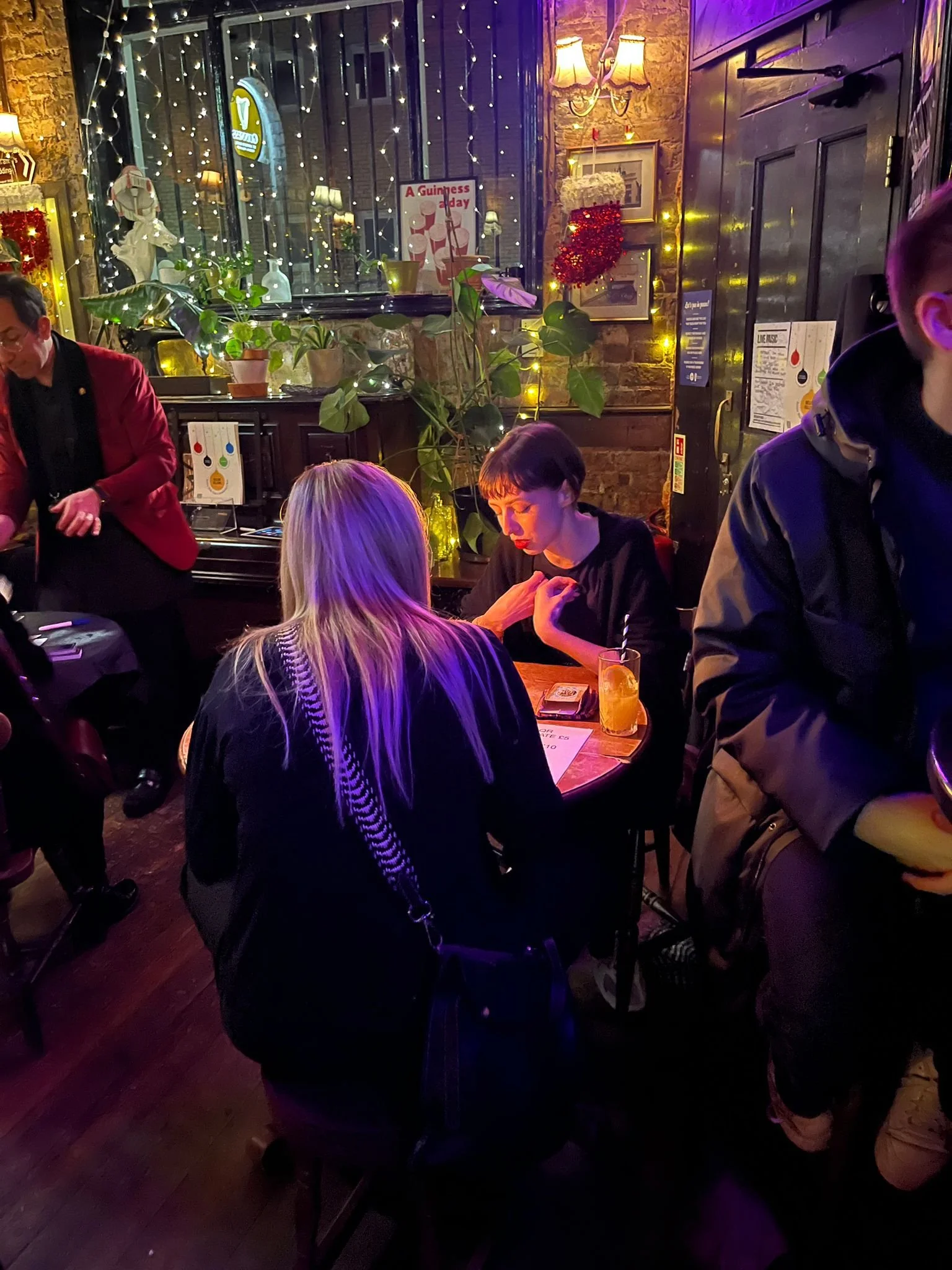 Georgia Preece sat in a cosy pub environment during a film screening event, she is giving Tarot Readings to a lady sat in front of her.