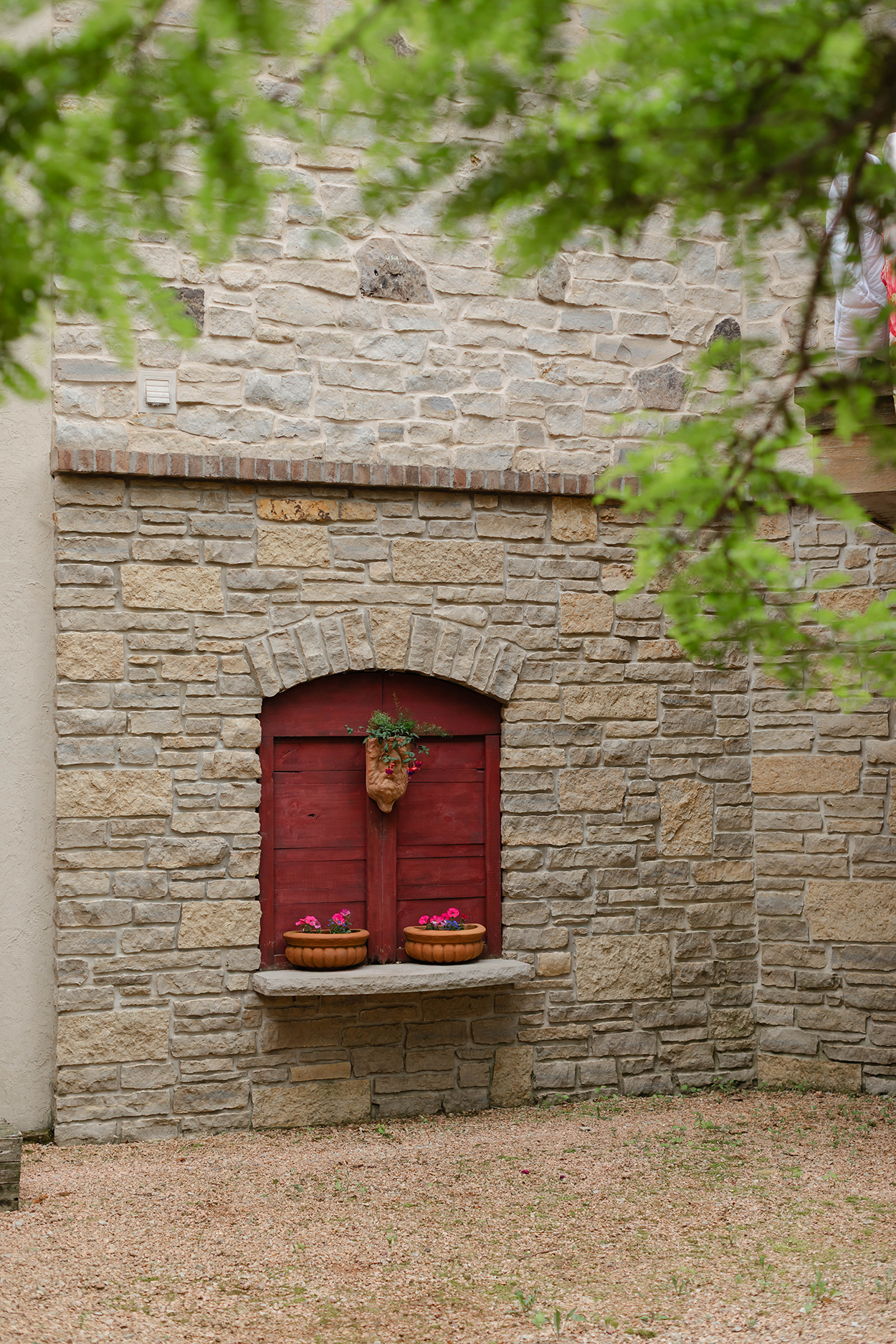 Stone wall with closed red wood shutters and plants.