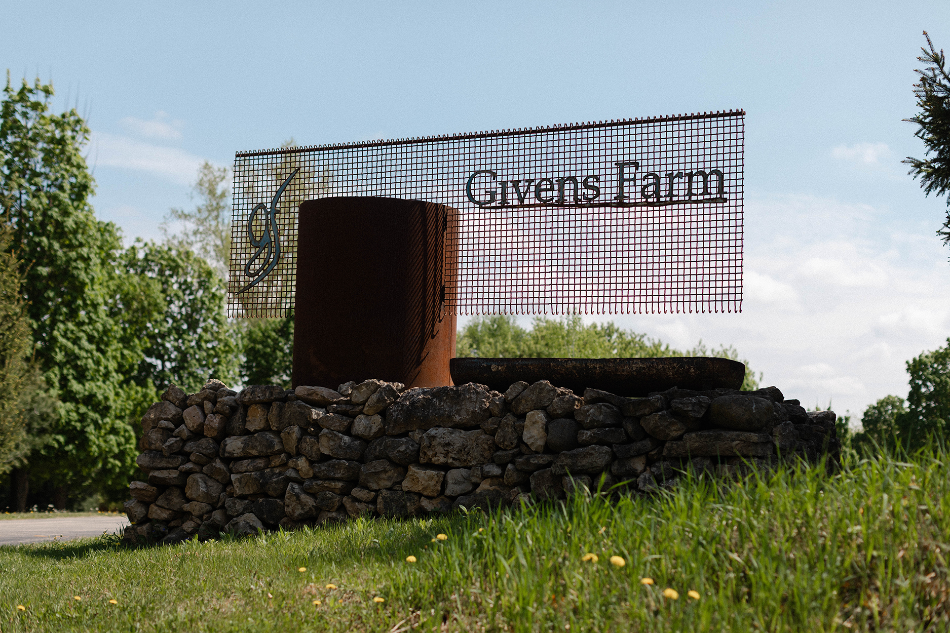Givens Farm metal sign with a clear sky in the background.