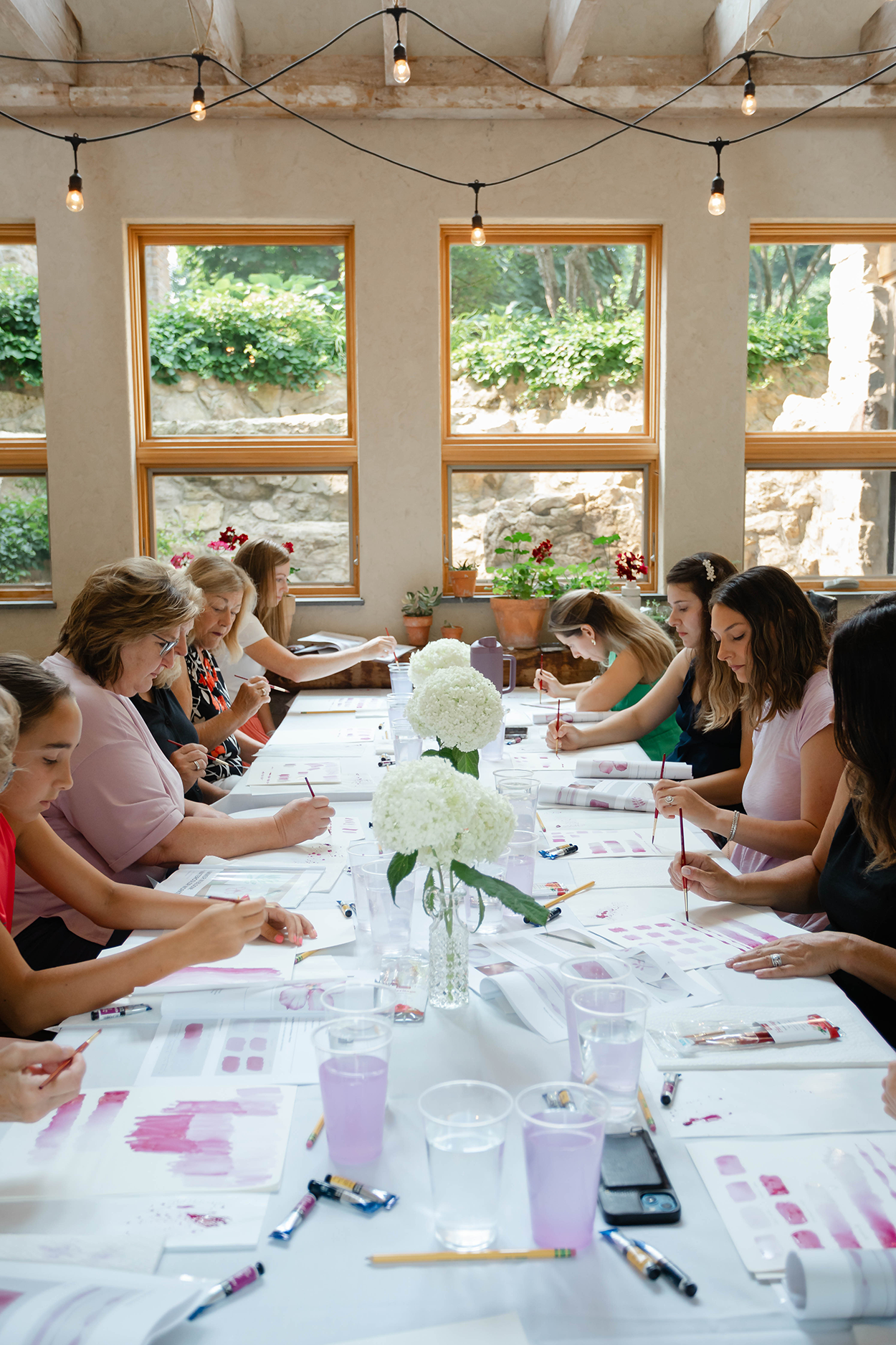 Watercolor class hosted on a long table with white linens in a garden room.