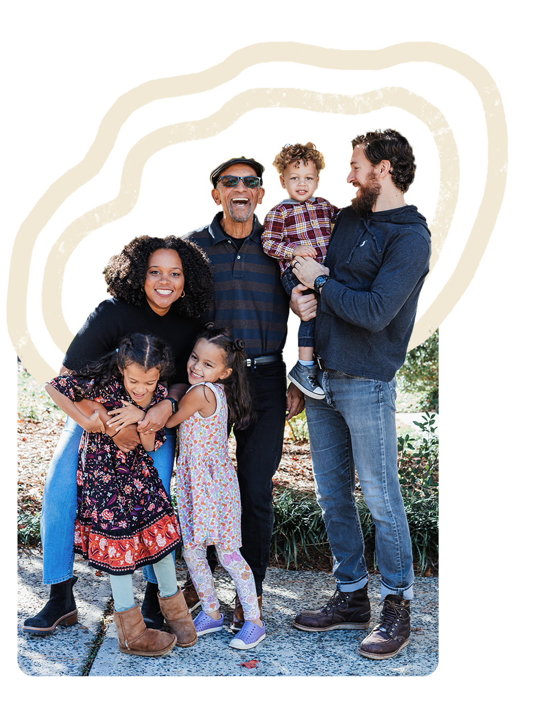 Family outdoor photo with three adults and three children, smiling and laughing.