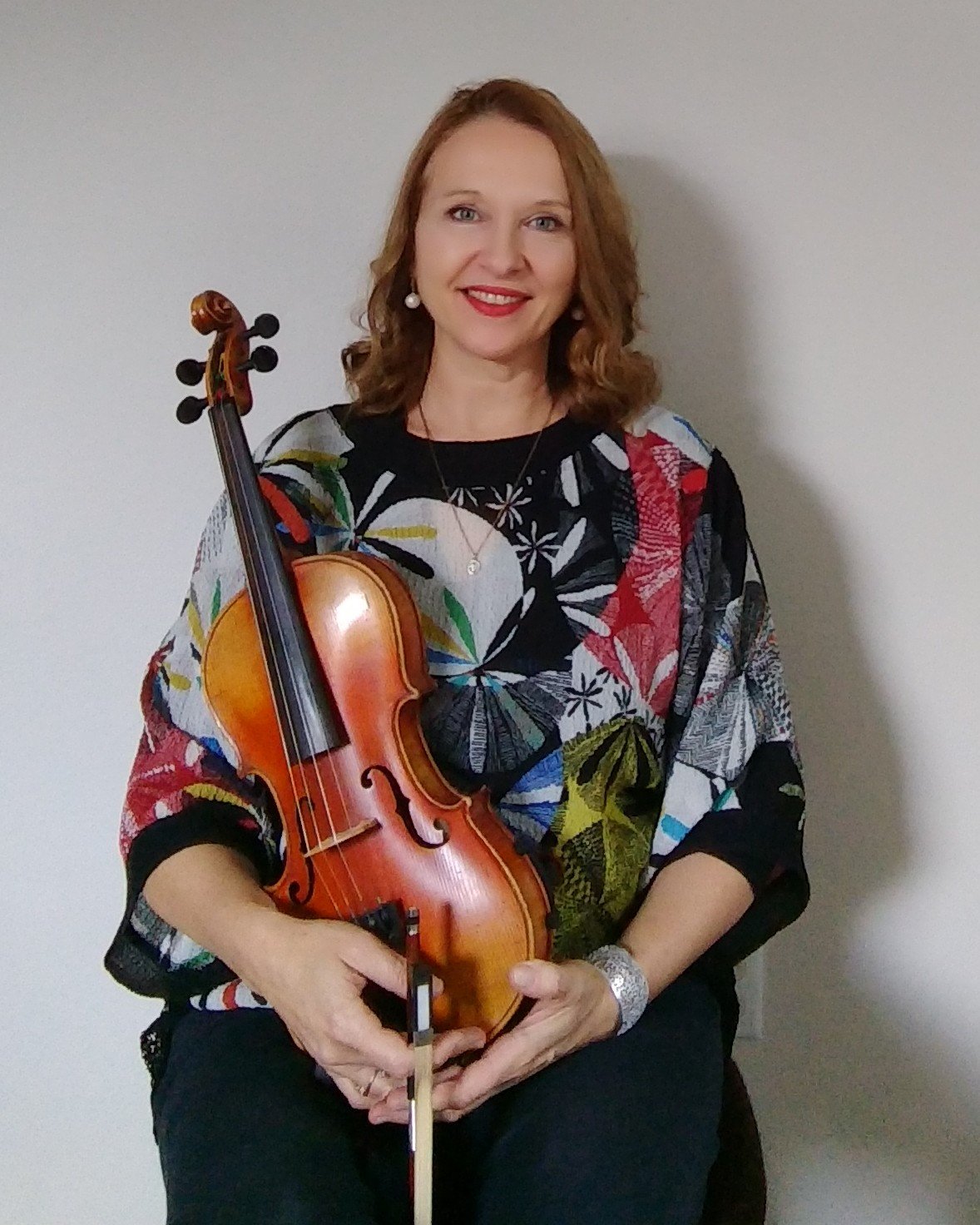 Woman in a colorful top holding a violin