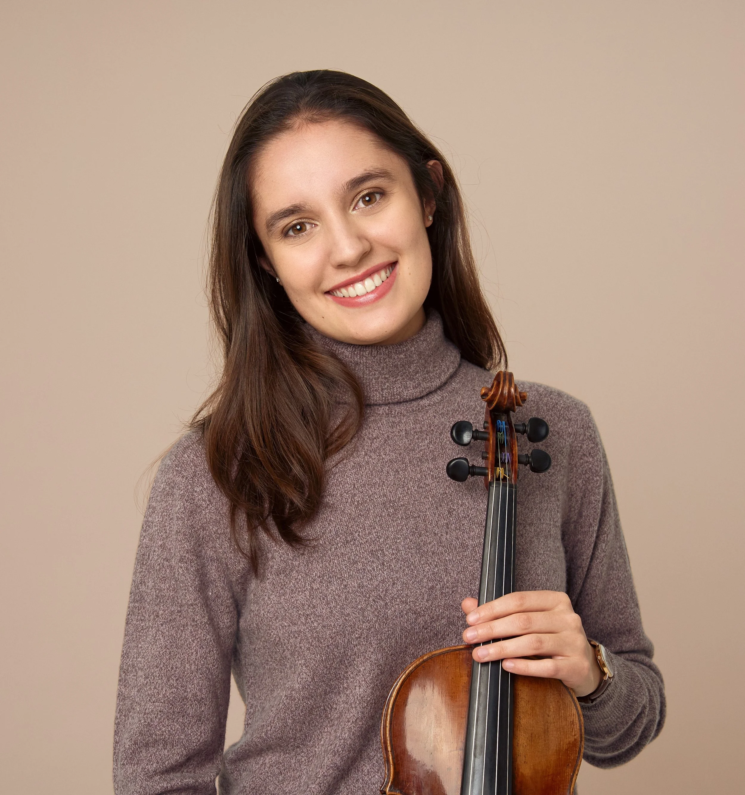 Smiling woman in a turtleneck sweater holding a violin
