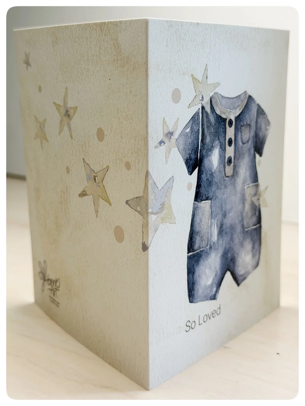 Side view of baby romper greeting card showing wrap around watercolour star artwork