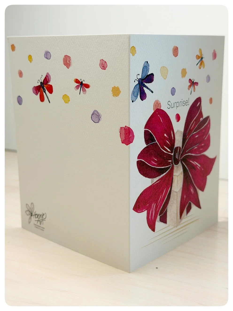 Side view of surprise gift bow greeting card showing wrap around watercolour dragonflies and colourful dots