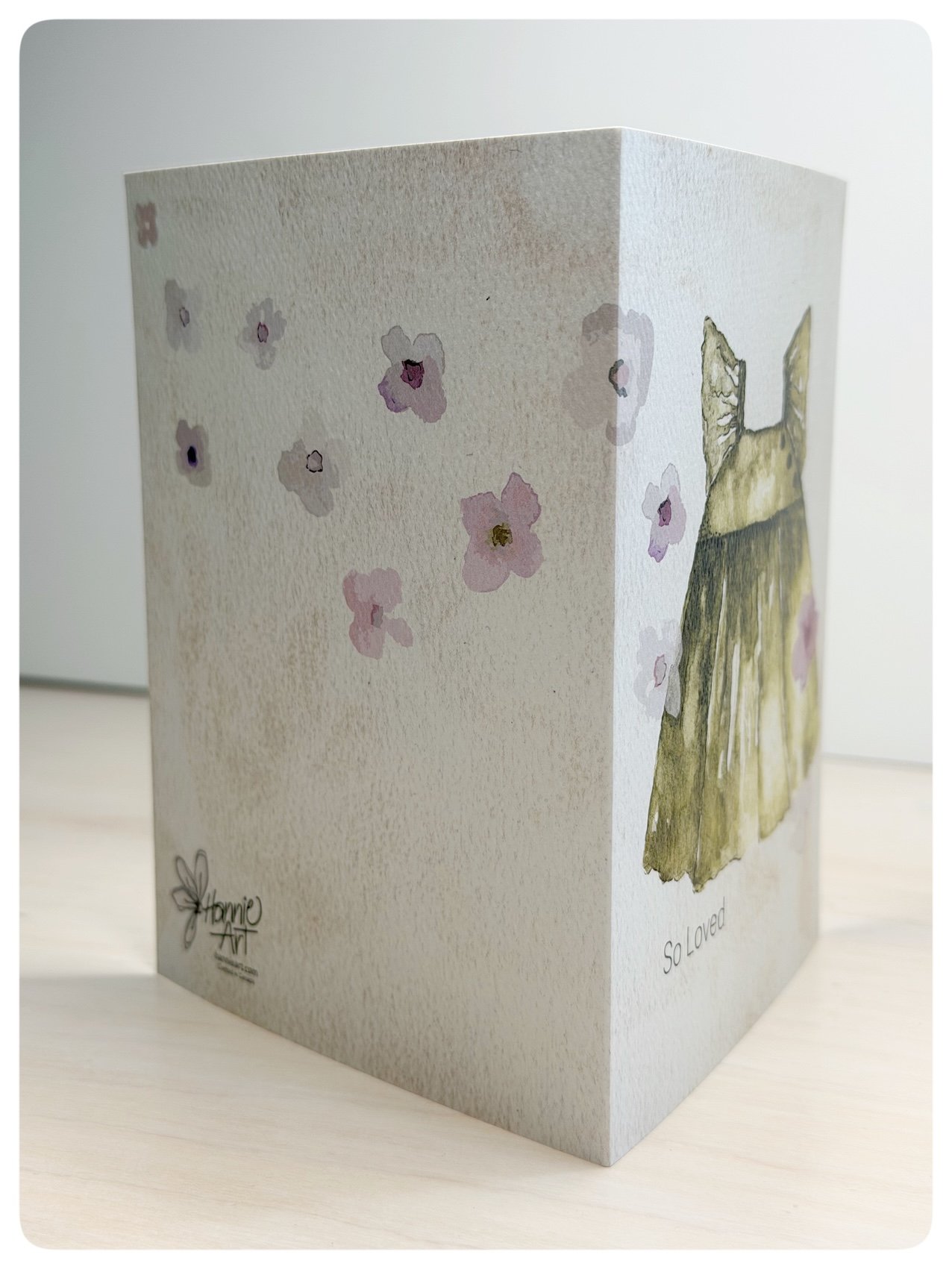 Side view of baby girl pinafore greeting card showing wraparound floral artwork