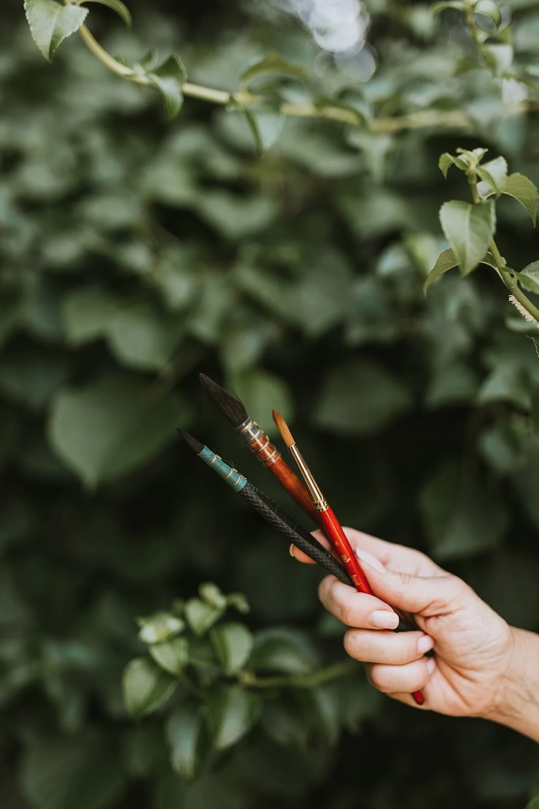 Watercolour brushes held in the garden, reflecting the natural inspiration behind the Hannie Art Studio creative process.