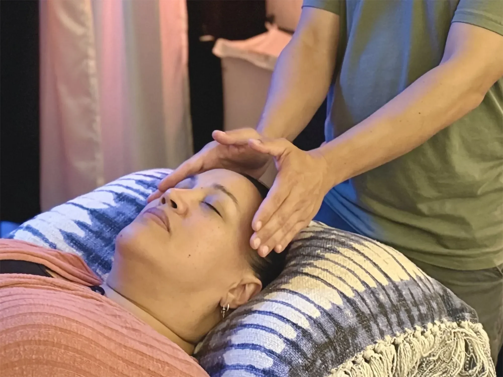 Person receiving reiki while lying on a pillow.