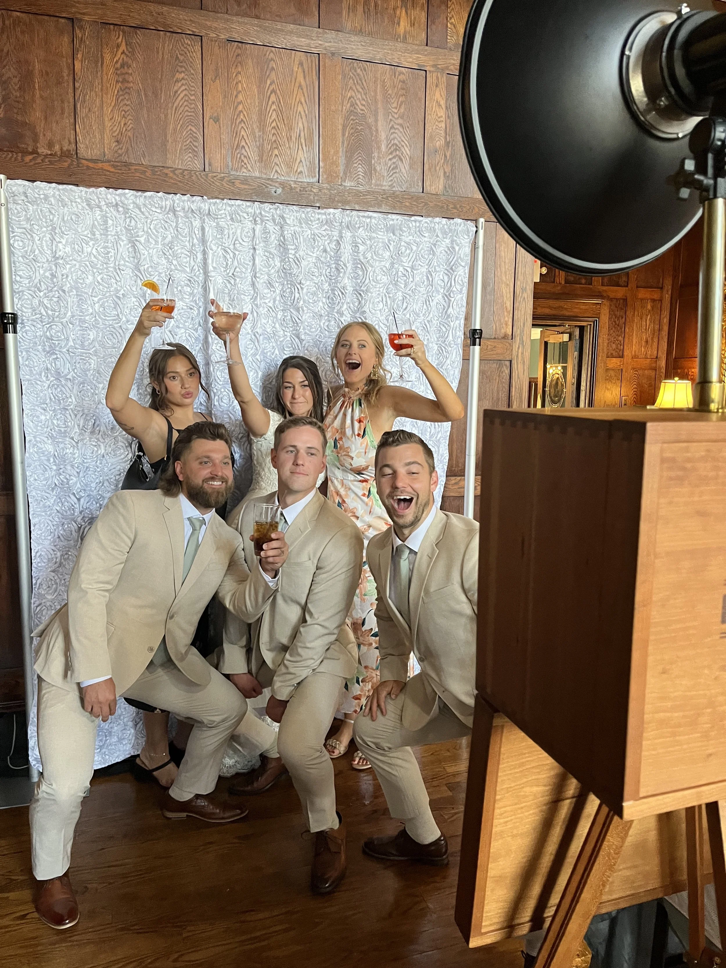 group of friends using photo booth rental at party event with drinks