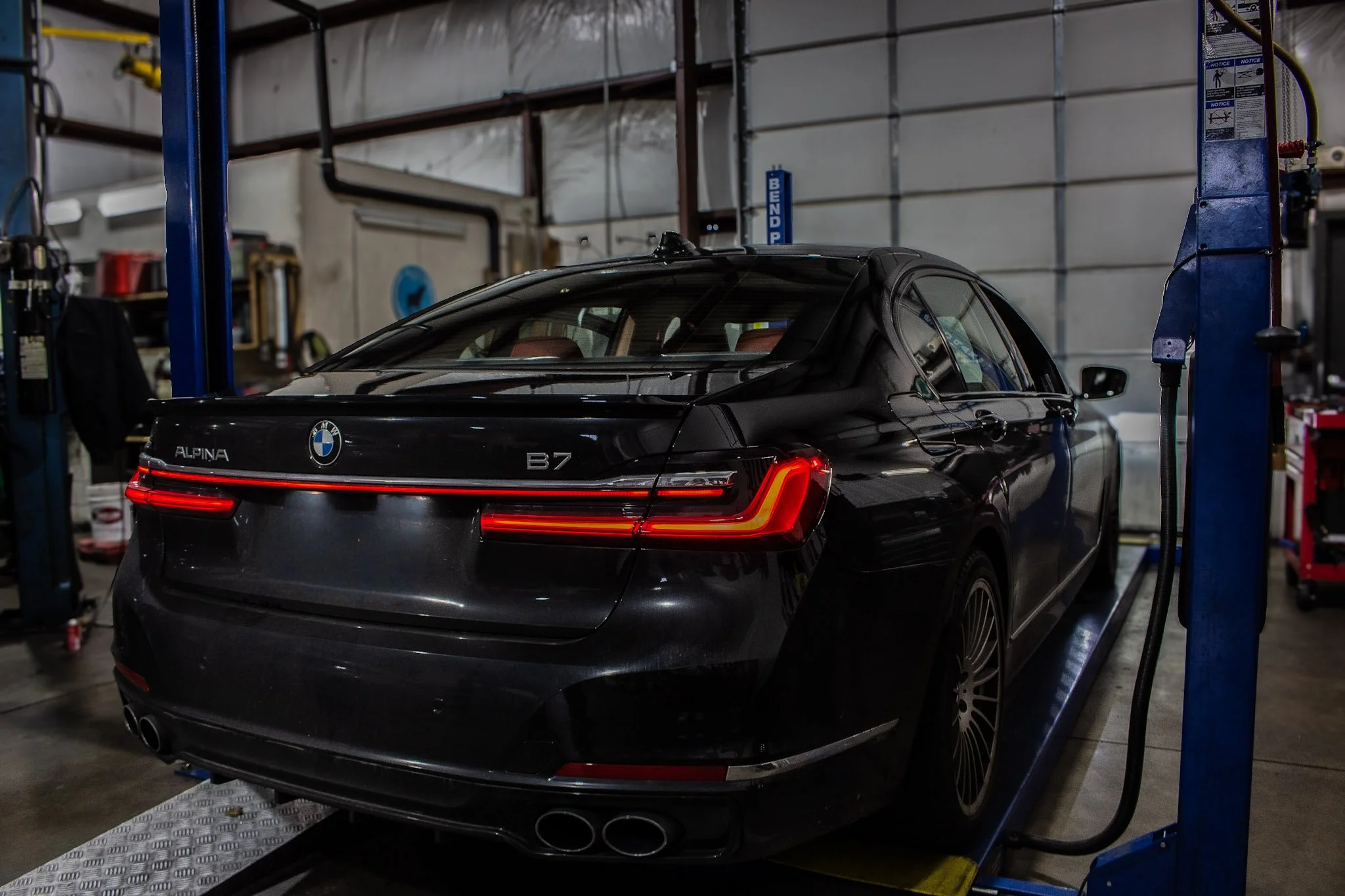 Black BMW Alpina B7 parked inside a garage or workshop.