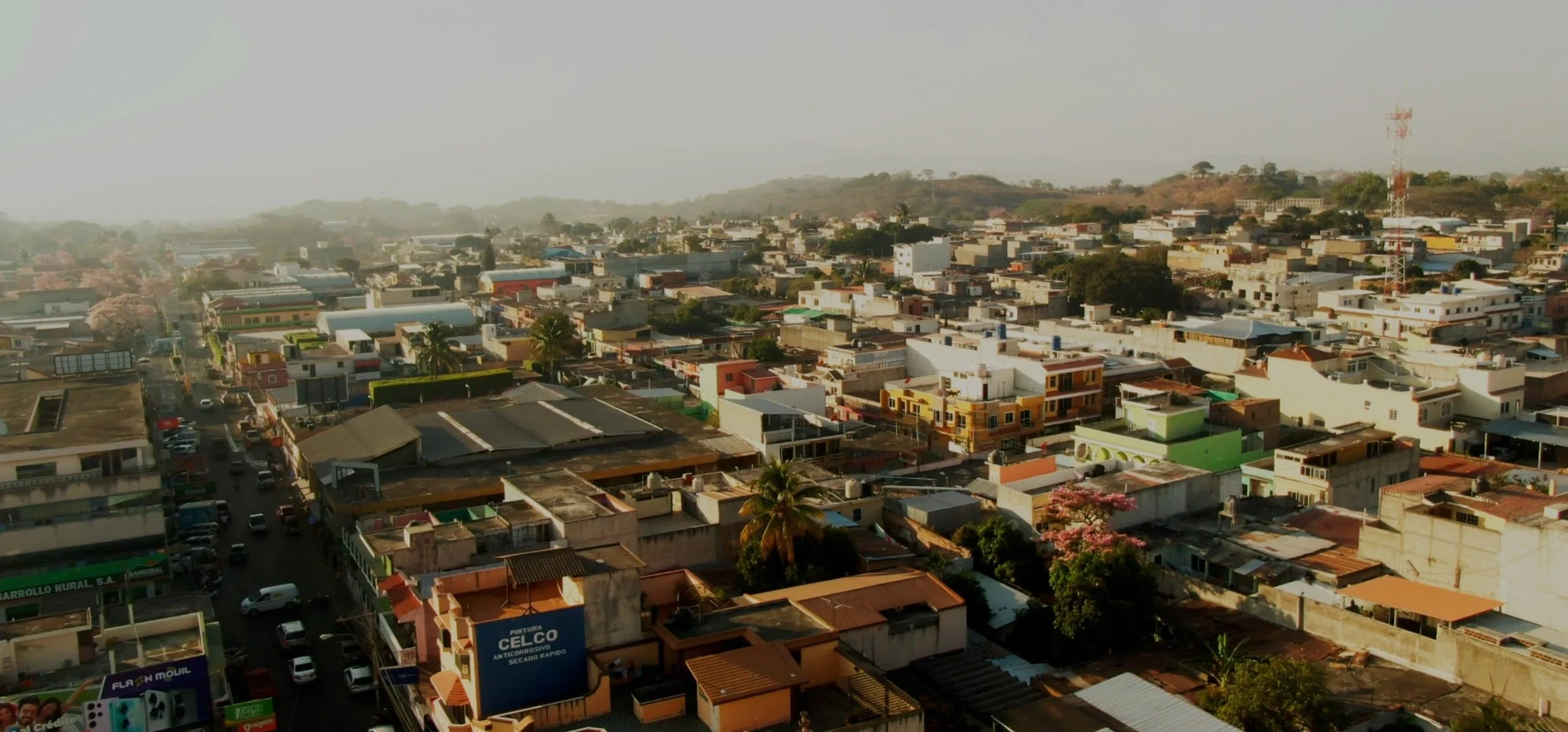 Aerial view of Jutiapa, a densely populated town with colorful buildings, trees, and hills in the background.