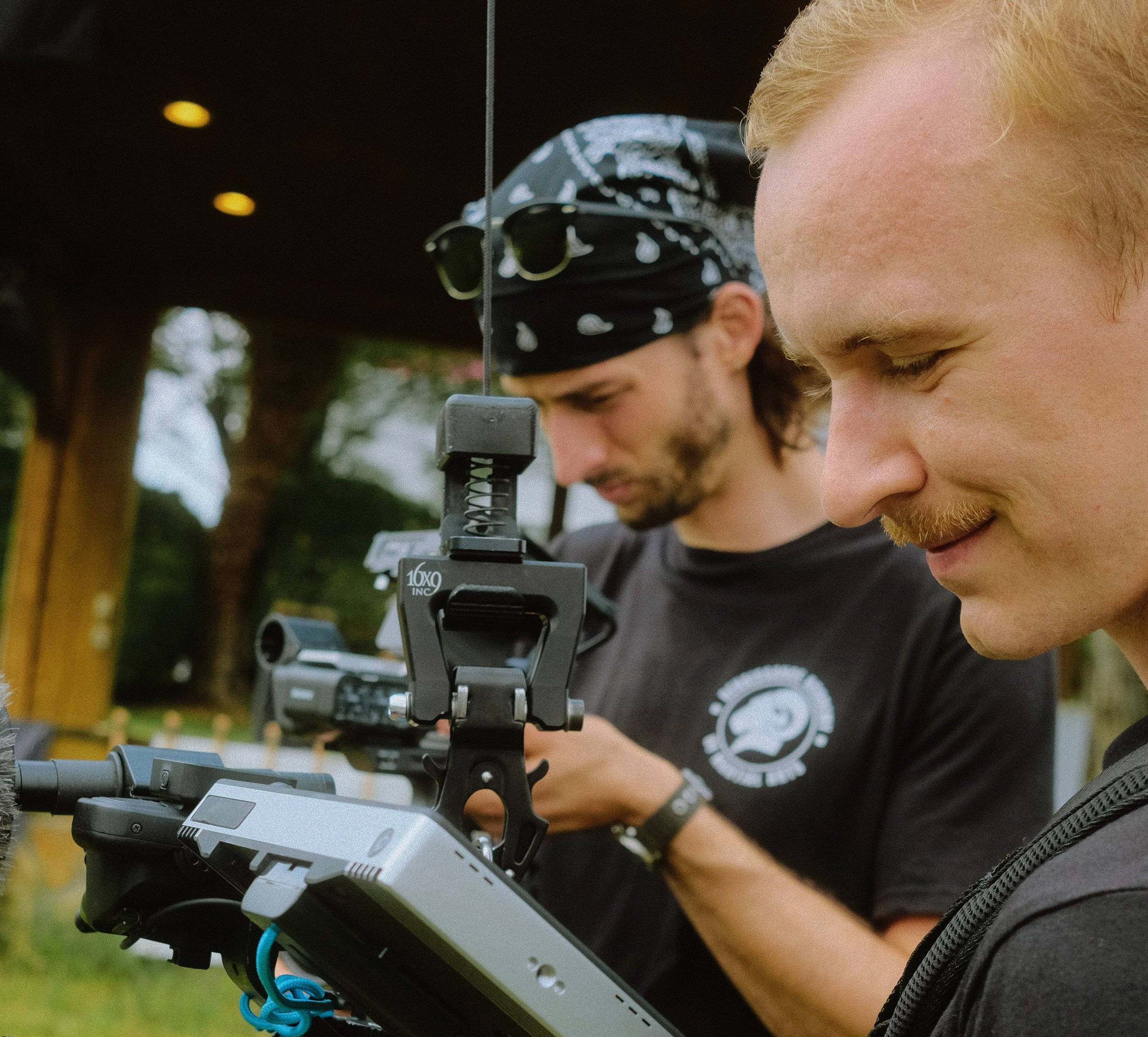 Two men operating professional cameras and filming equipment outdoors.