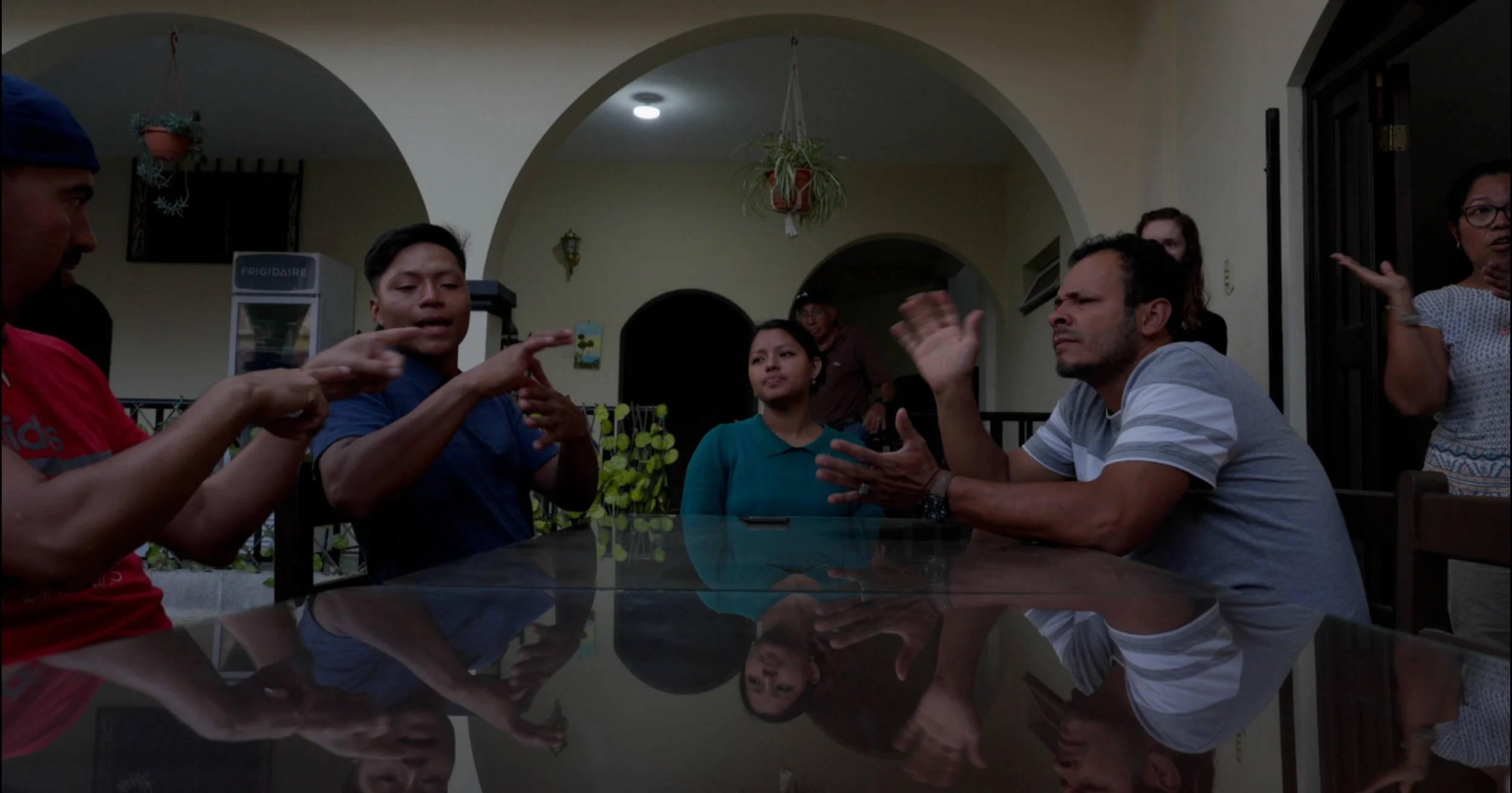 Group of deaf people engaged in a serious discussion around a table in a living room.