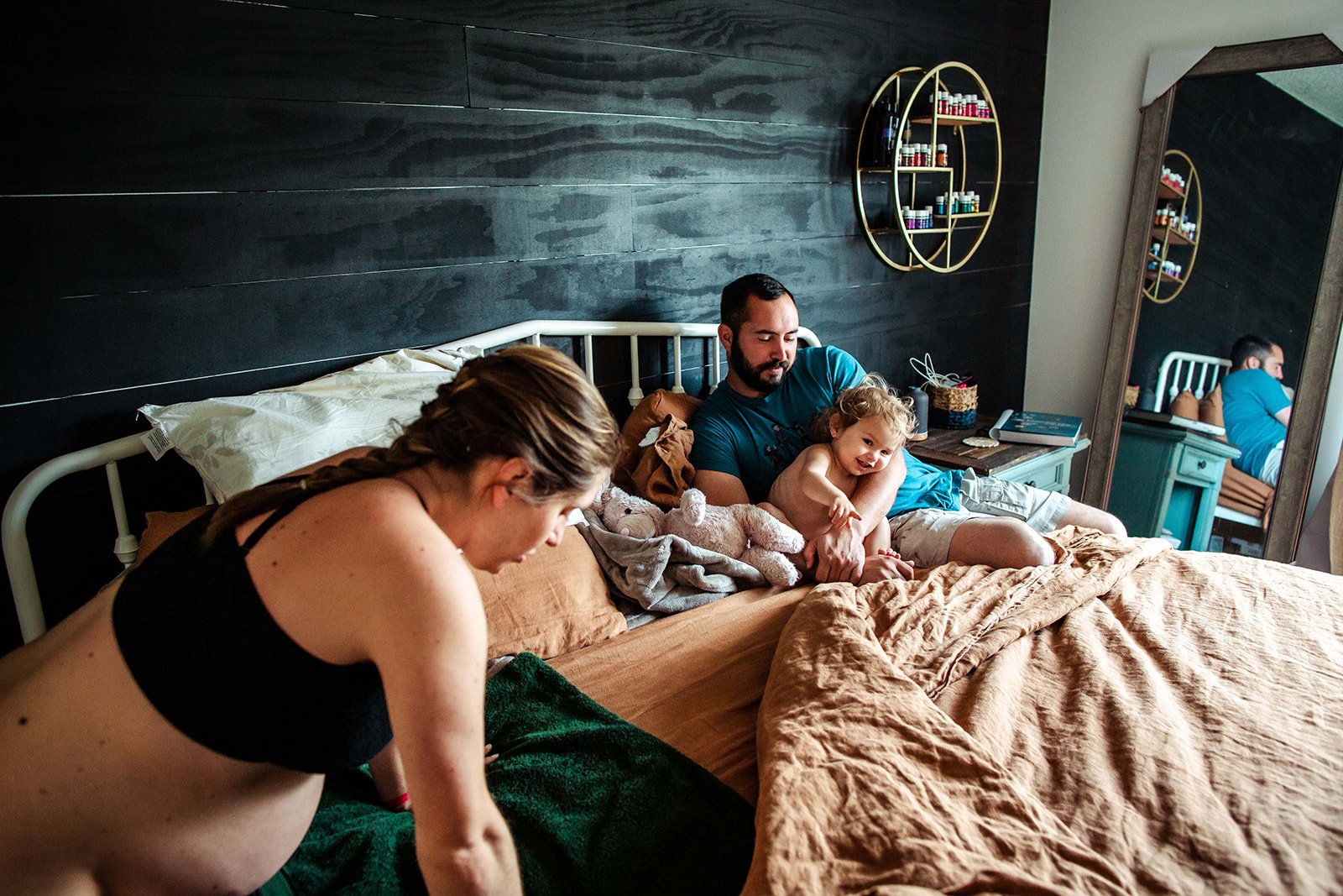 A laboring woman bending over on a bed in her bedroom with family present. Home birth, water birth, prenatal and postpartum midwifery care, Pooler, GA, Savannah, GA Midwife