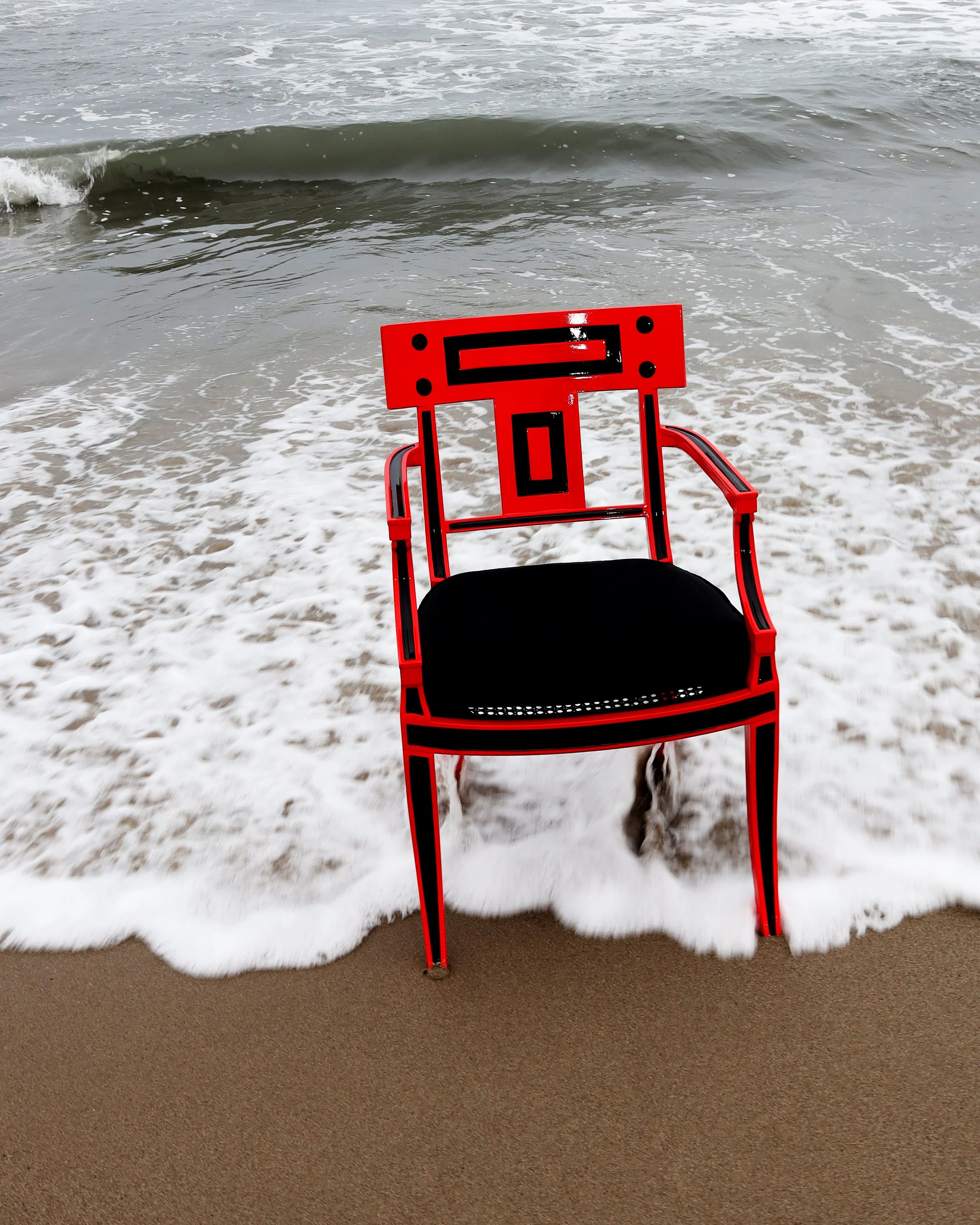 Orange beach rescue chair on wet sand with foamy waves in the background.