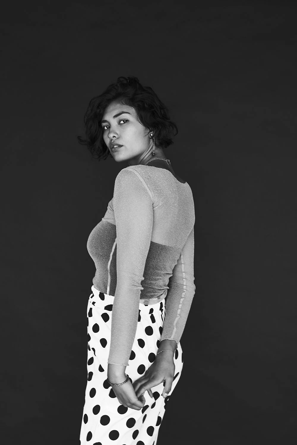 Black-and-white standing portrait in a patterned skirt