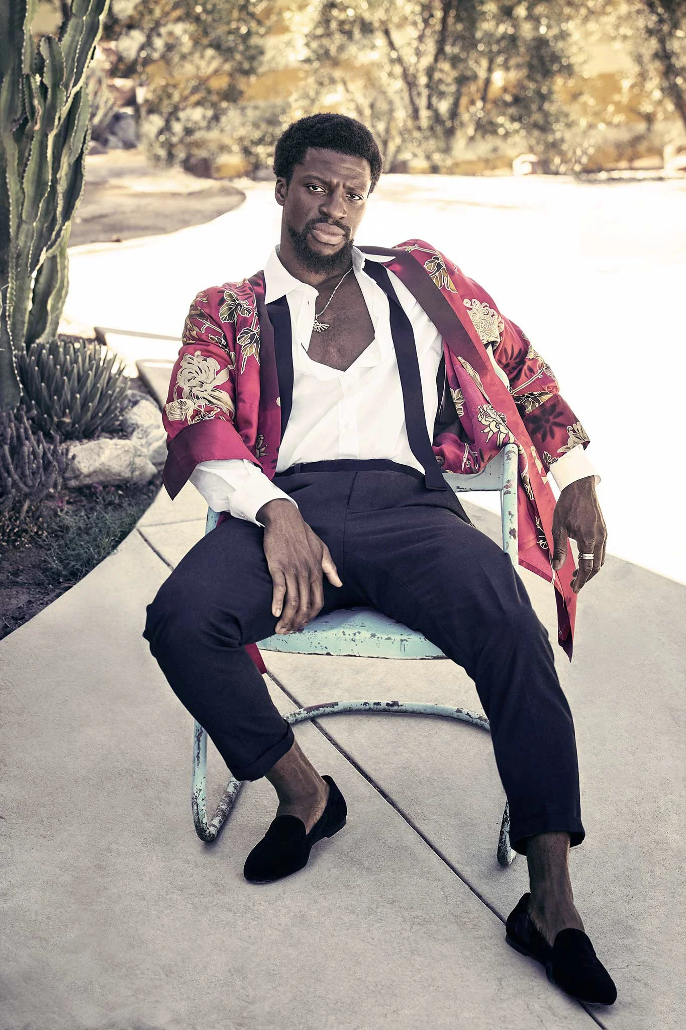 Man in a floral blazer and white shirt sitting outdoors on a chair