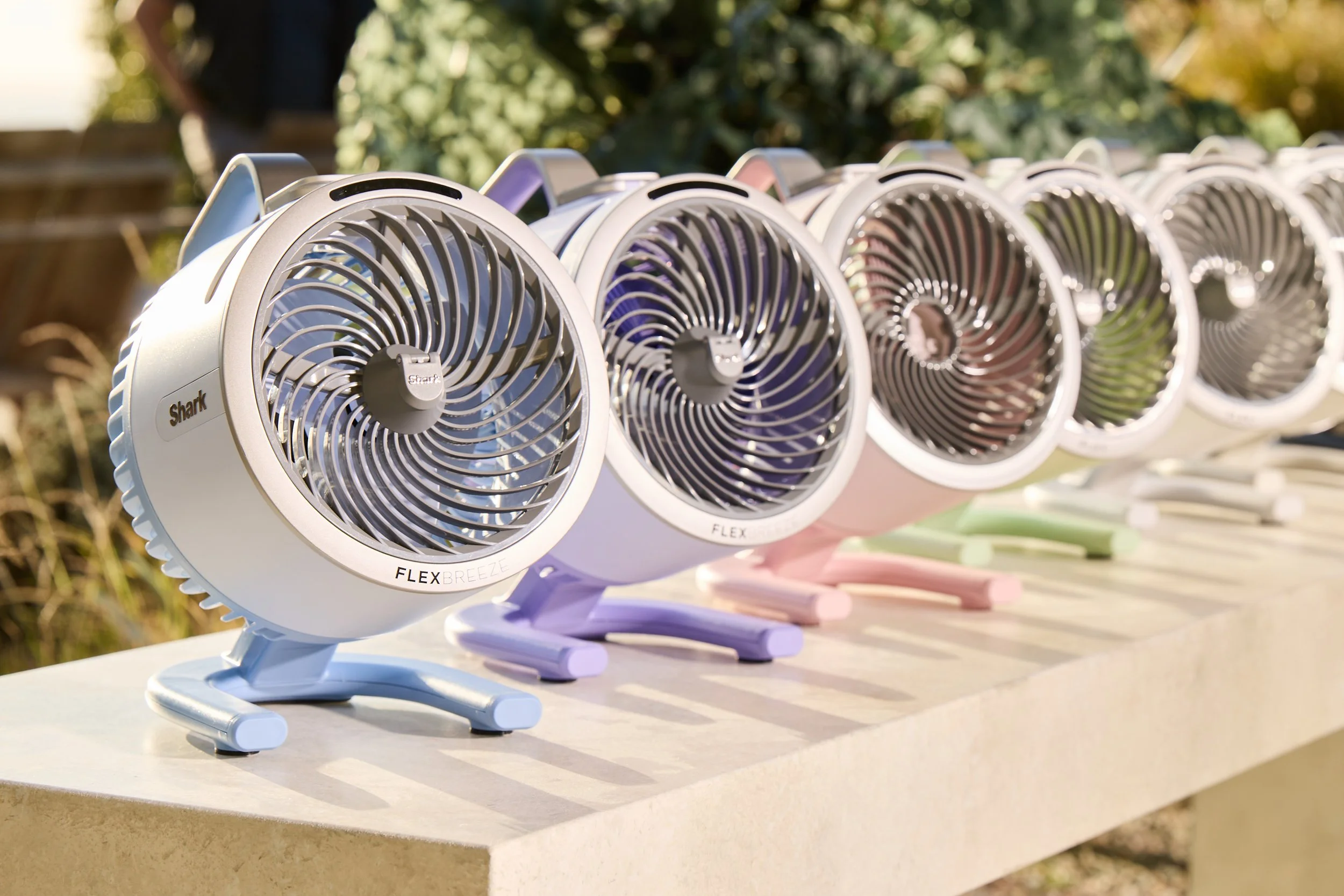 Row of Shark Flex Breeze fans in different colors on a table.