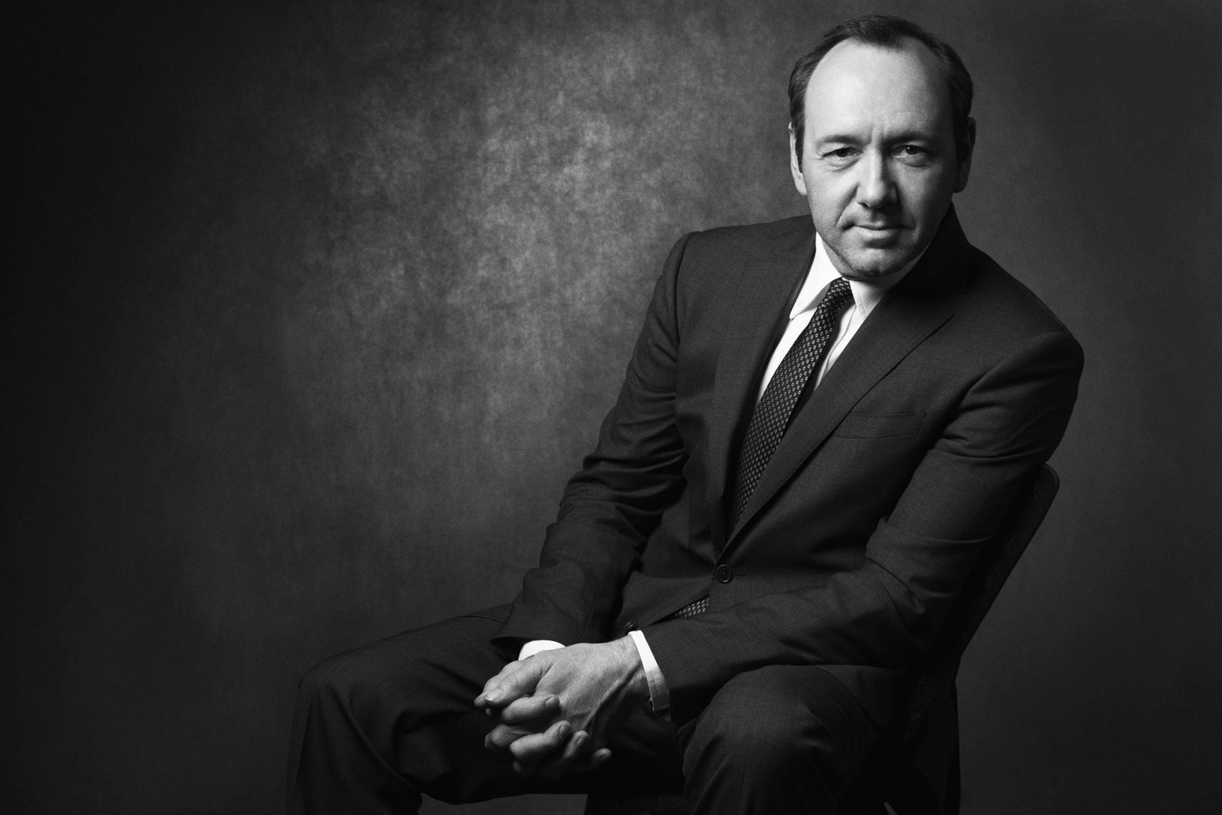 Black-and-white seated portrait in a dark suit