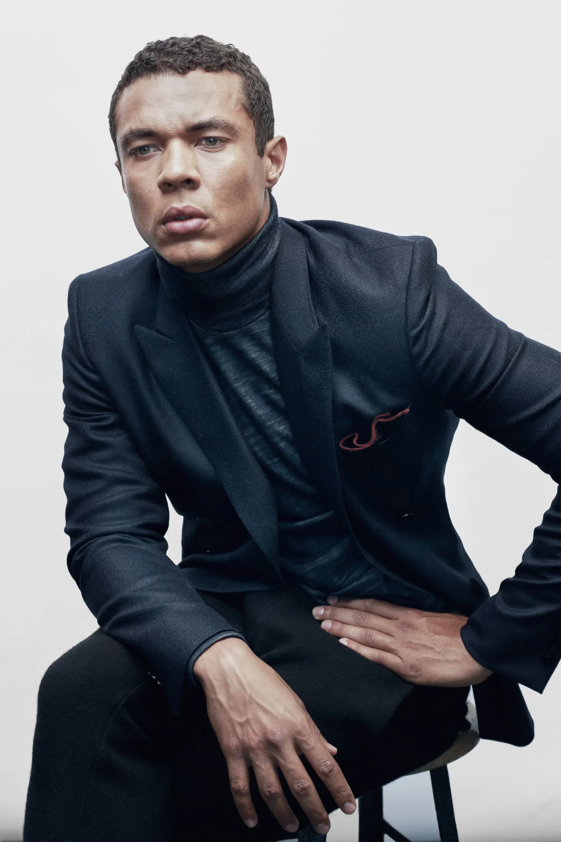 Seated portrait in a dark suit and turtleneck