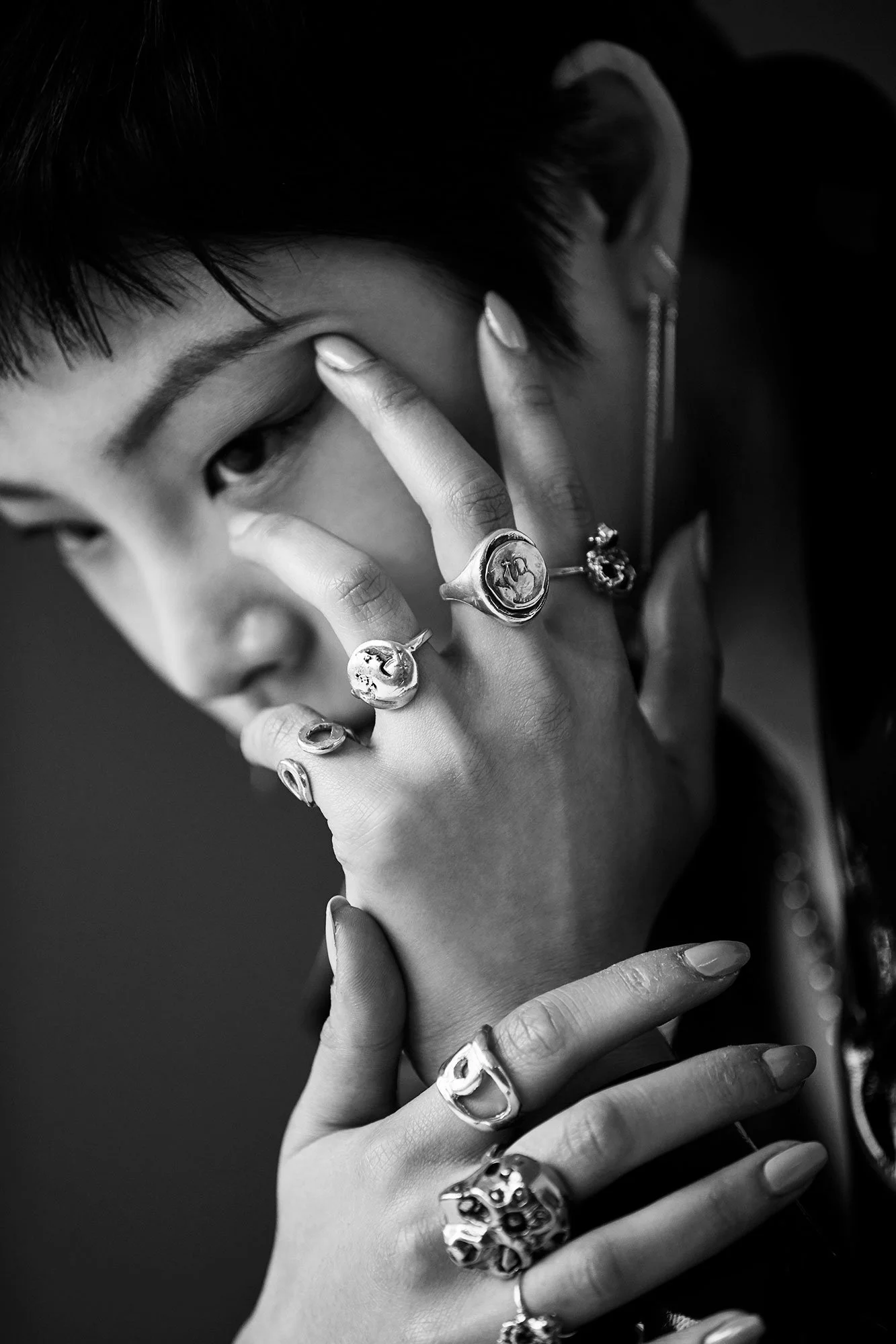 Black-and-white close portrait with ring-covered hands