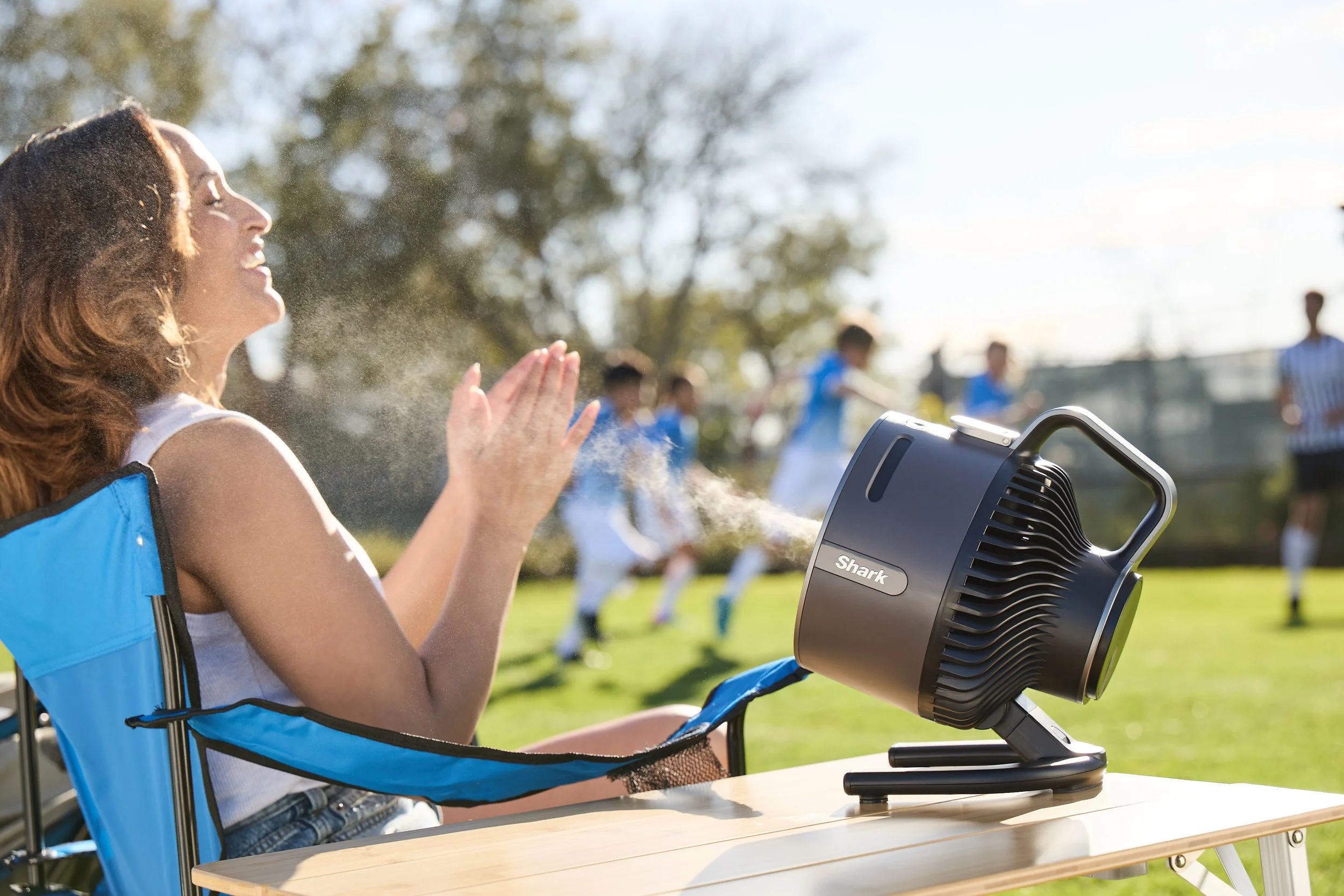 Woman enjoying mist from a Shark fan at a soccer game.