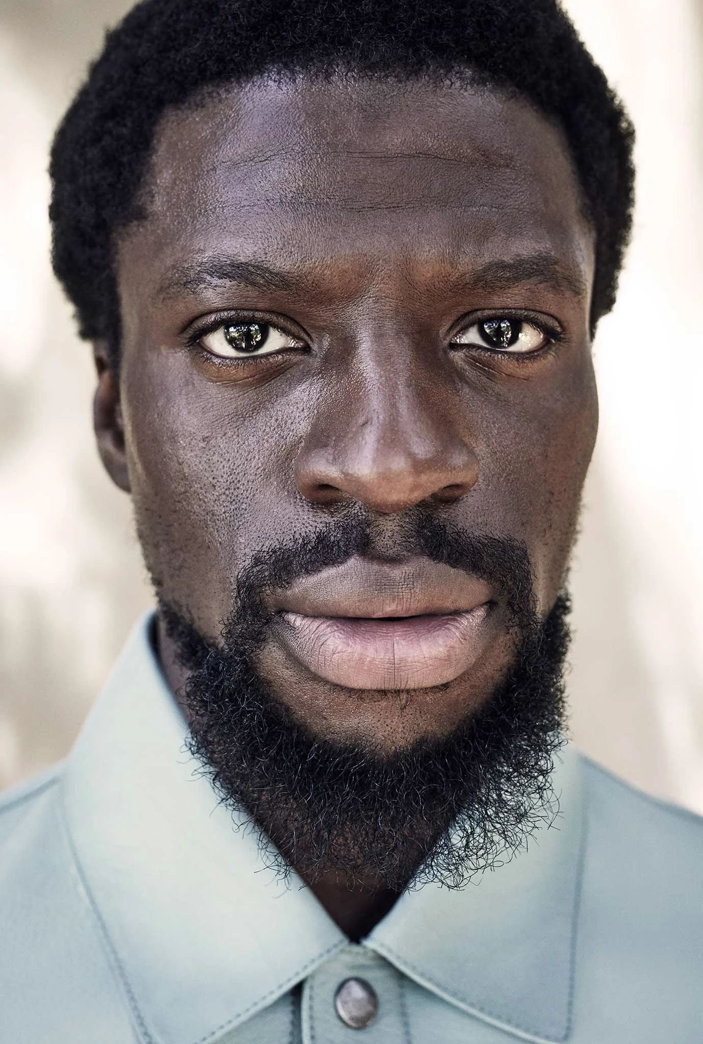 Close-up portrait of a man with a beard, wearing a light-colored shirt.