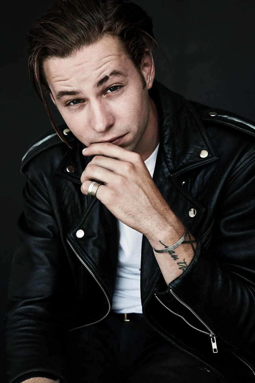 Portrait in a leather jacket with a hand near the mouth