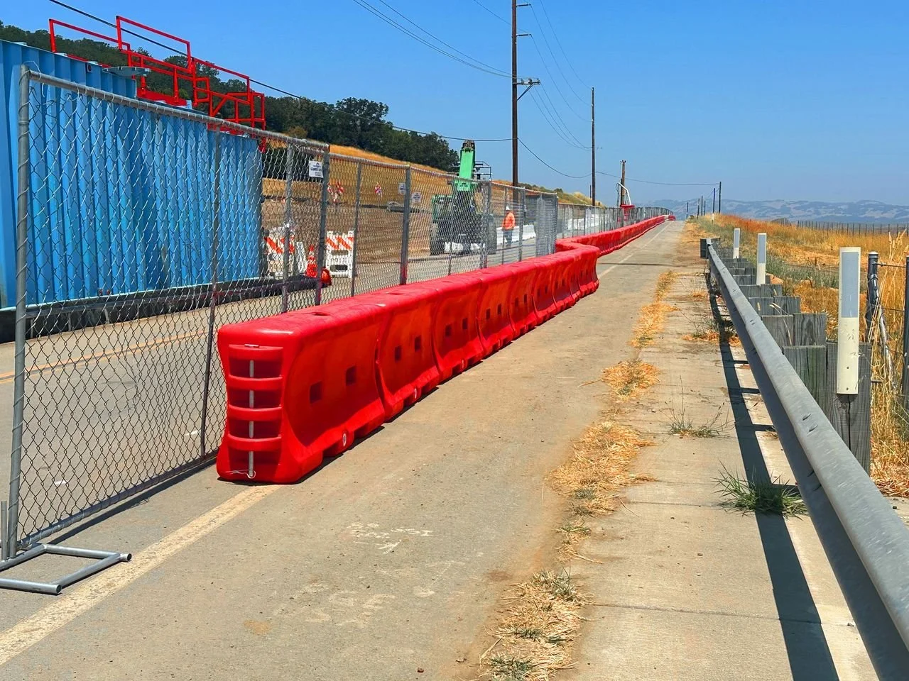 A construction site in Vacaville, CA with water wall barrier, jobsite security fencing, and temporary utility poles