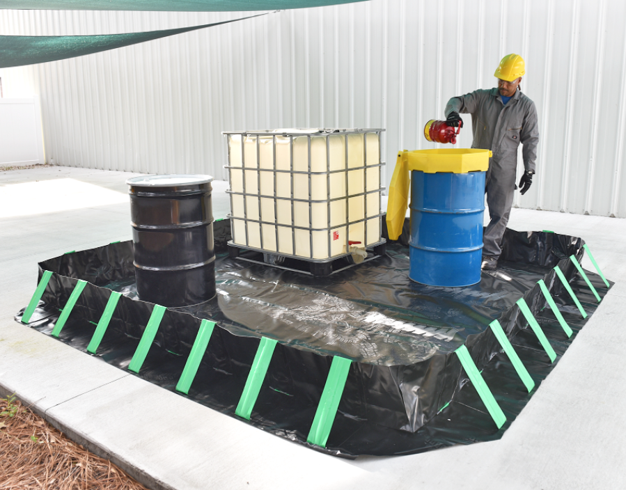 worker filling fuel drum in a spill containment berm.webp